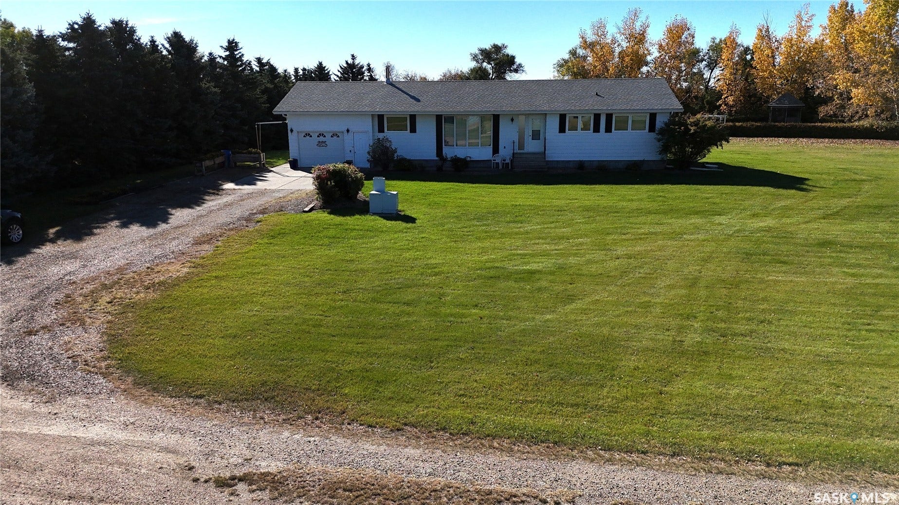 Ranch-style residence featuring a gravel drive, attached two-car garage, and expansive front lawn