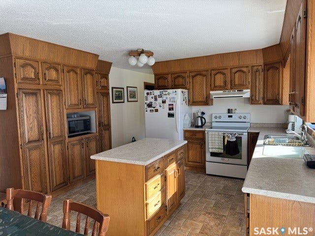 Wood-finish cabinetry with extensive storage, an integrated microwave space, and a matching center island with a light-toned countertop