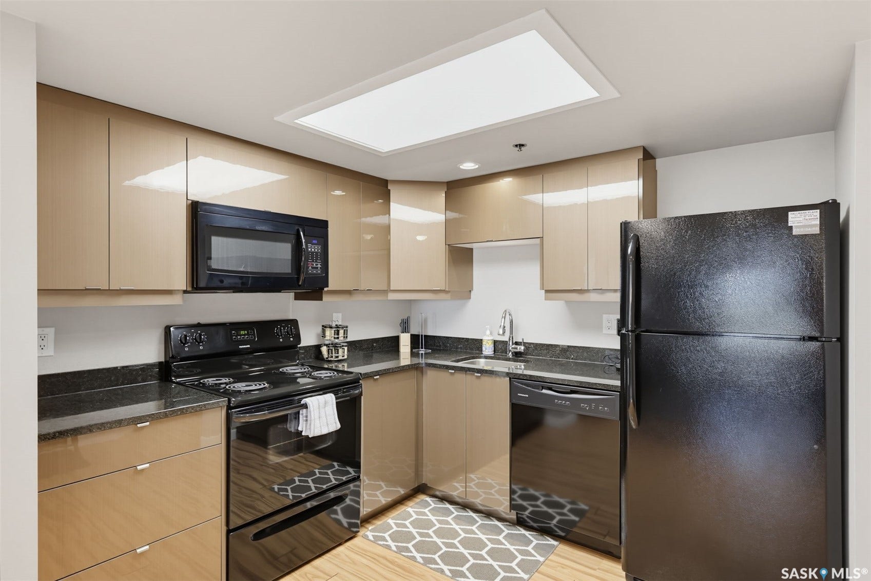 Kitchen featuring dark countertops, upper cabinetry, lower cabinetry, and black appliances