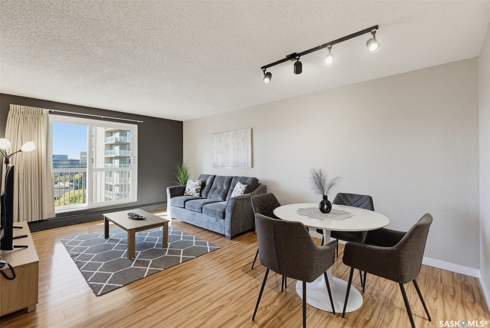 Wood-finish flooring, accent wall, track lighting, and a sliding glass door