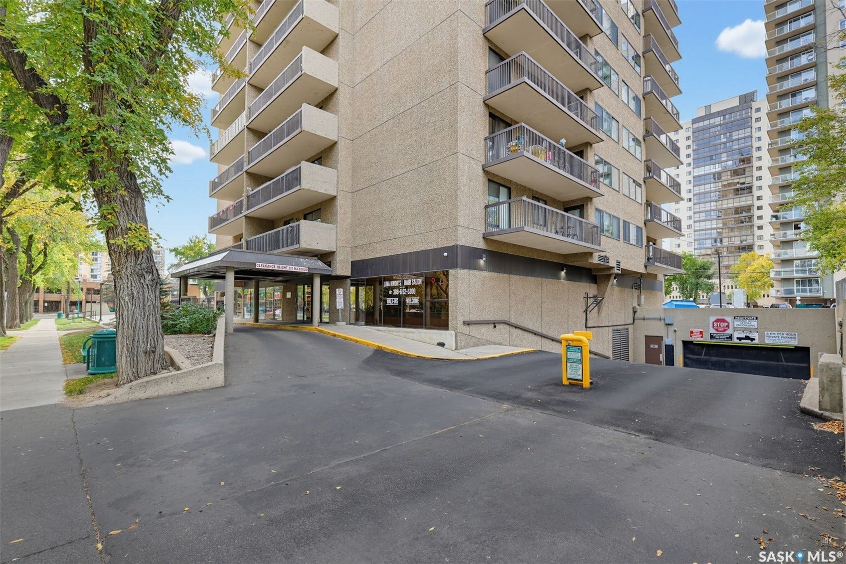 Multi-story building featuring individual balconies, a covered entrance, and an integrated underground parking ramp