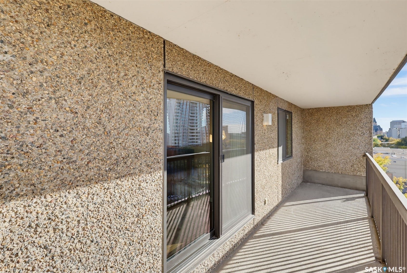 Exterior balcony featuring exposed aggregate walls and concrete flooring