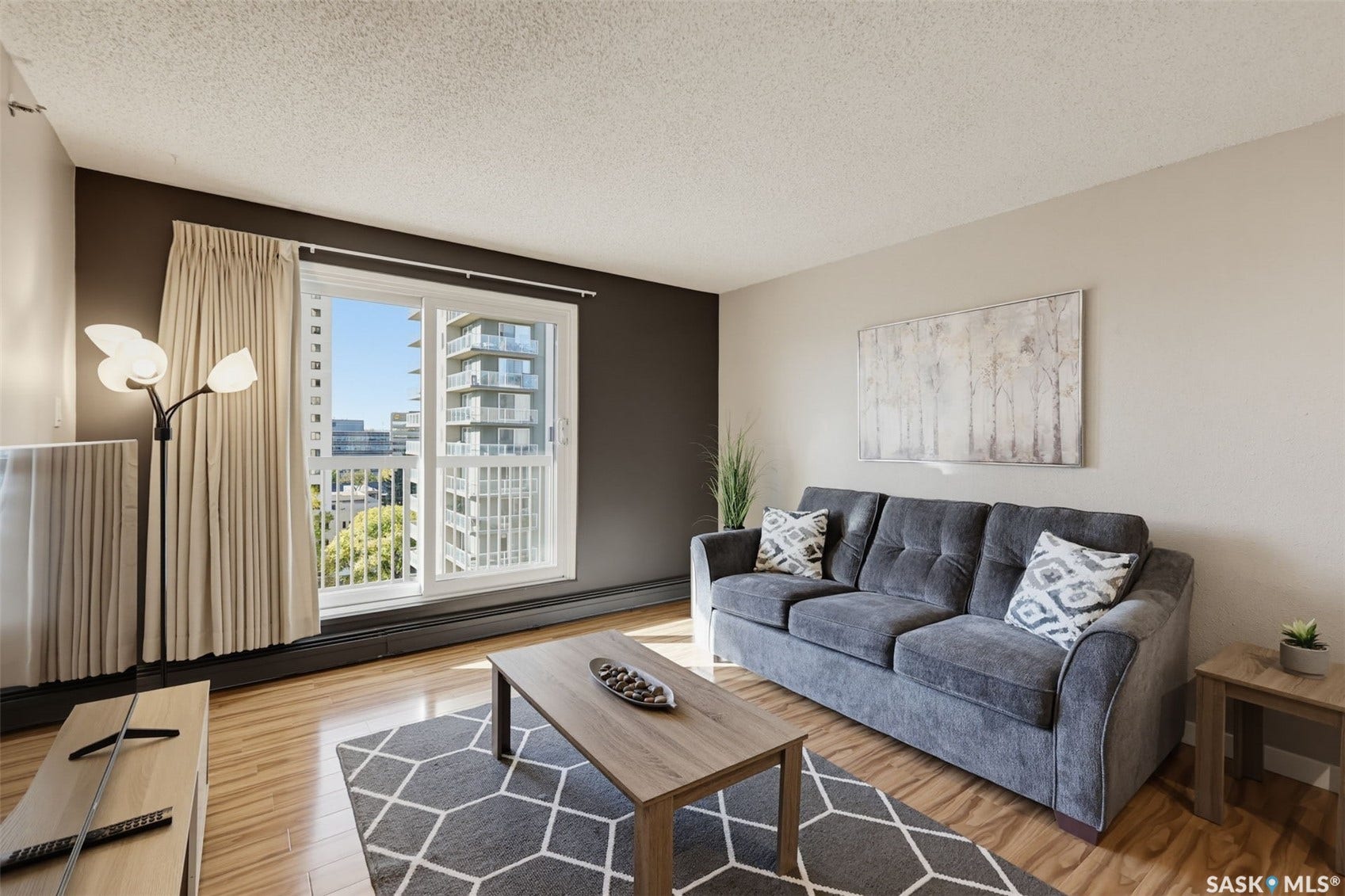 Wood-finish flooring throughout, featuring a large window with vertical blinds, and a neutral color palette