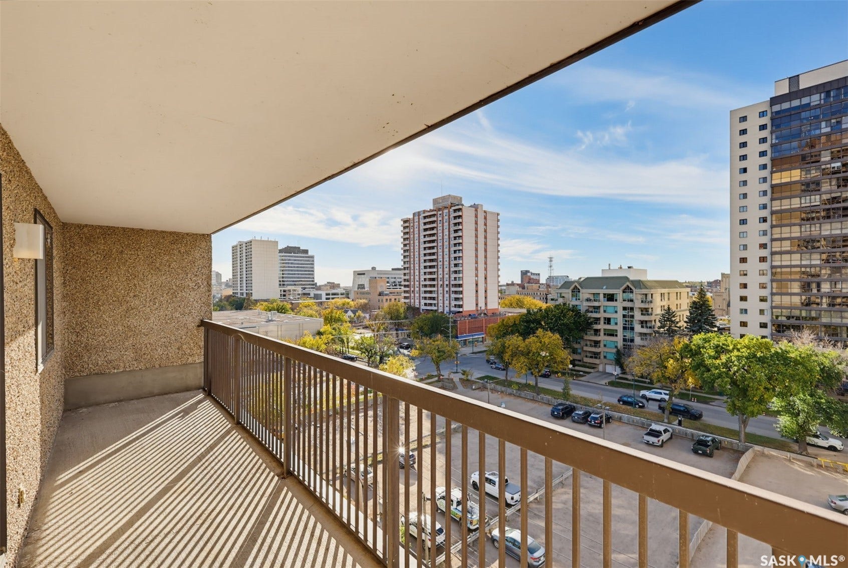 Balcony with textured exterior wall, metal railing, and urban landscape