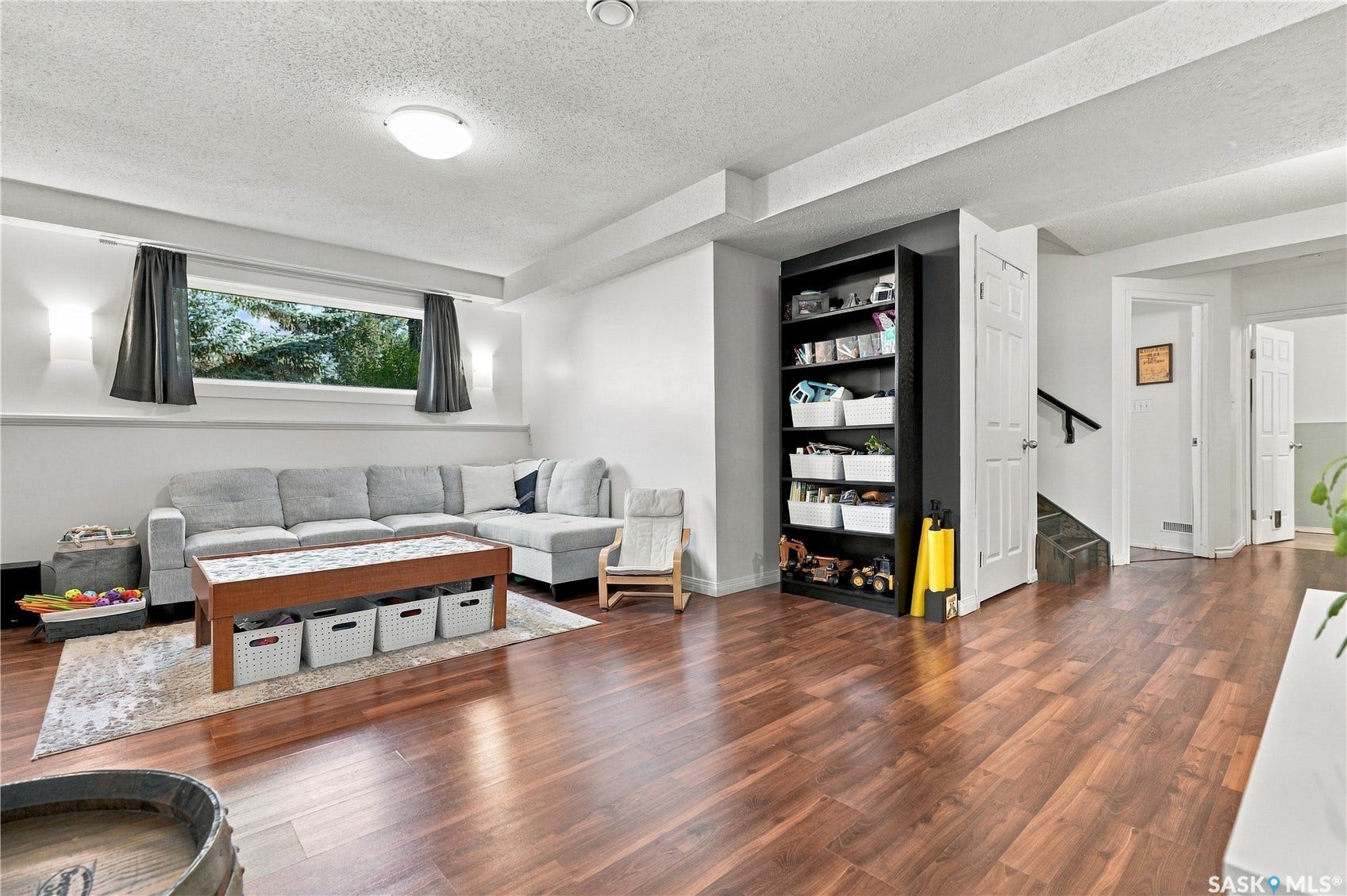 Expansive room featuring wood-finish flooring, a wide window, and a built-in shelving unit