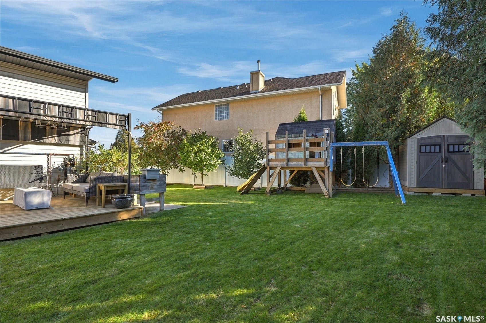 Expansive green lawn, large wood deck, and a detached storage shed