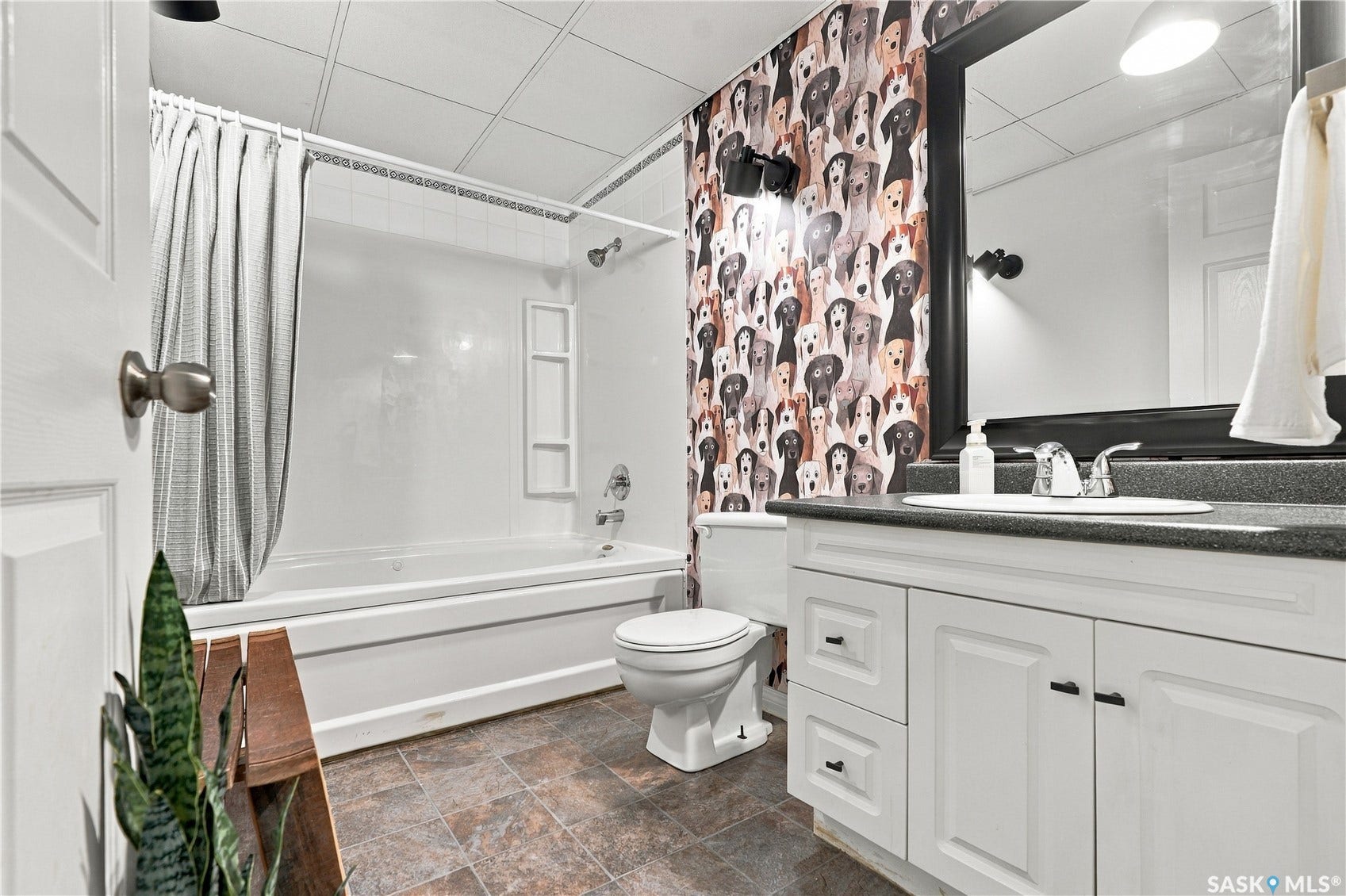 White vanity with cabinet storage, dark speckled countertop, and integrated sink
