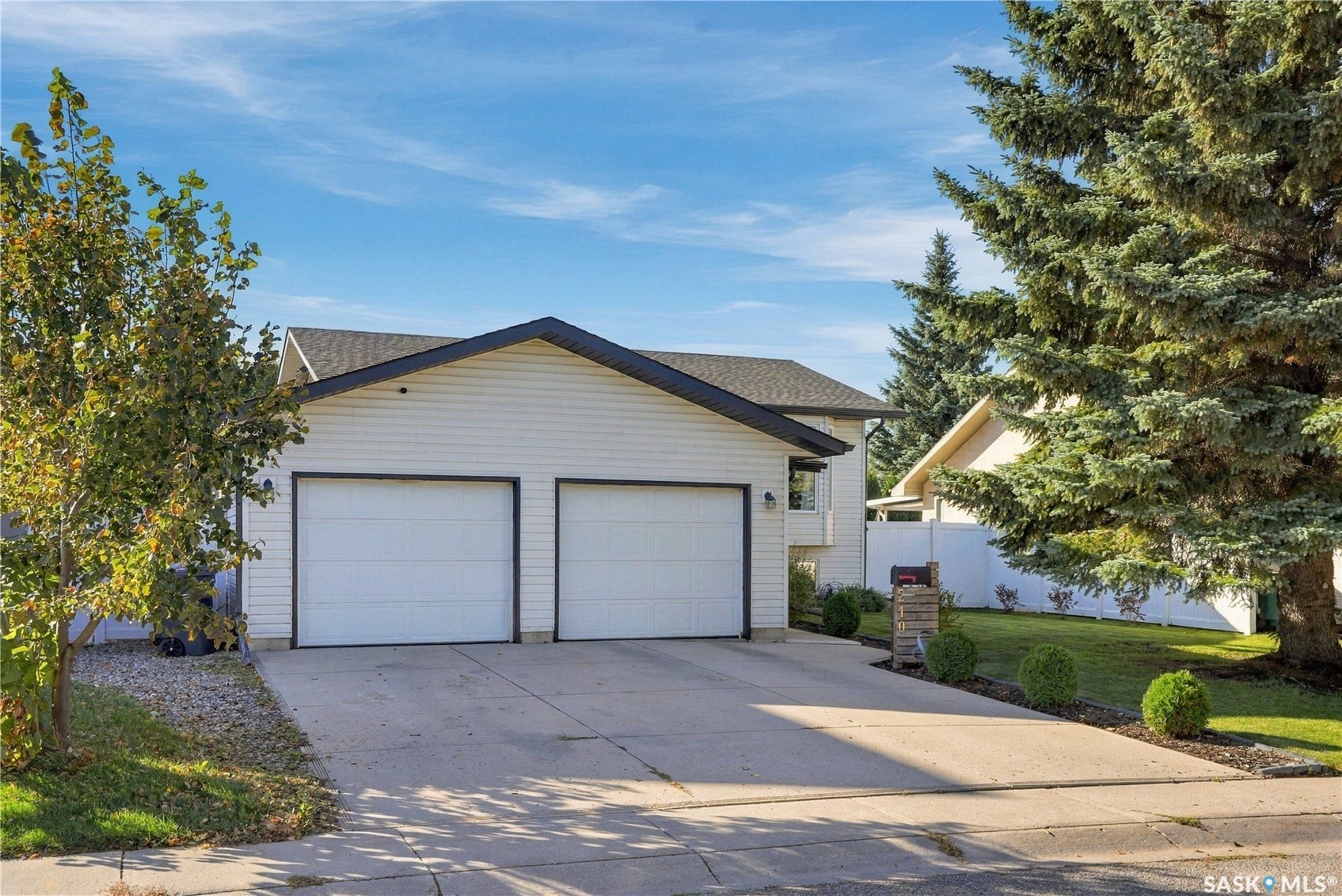 Two-car attached garage with concrete driveway, white siding exterior, and black trim