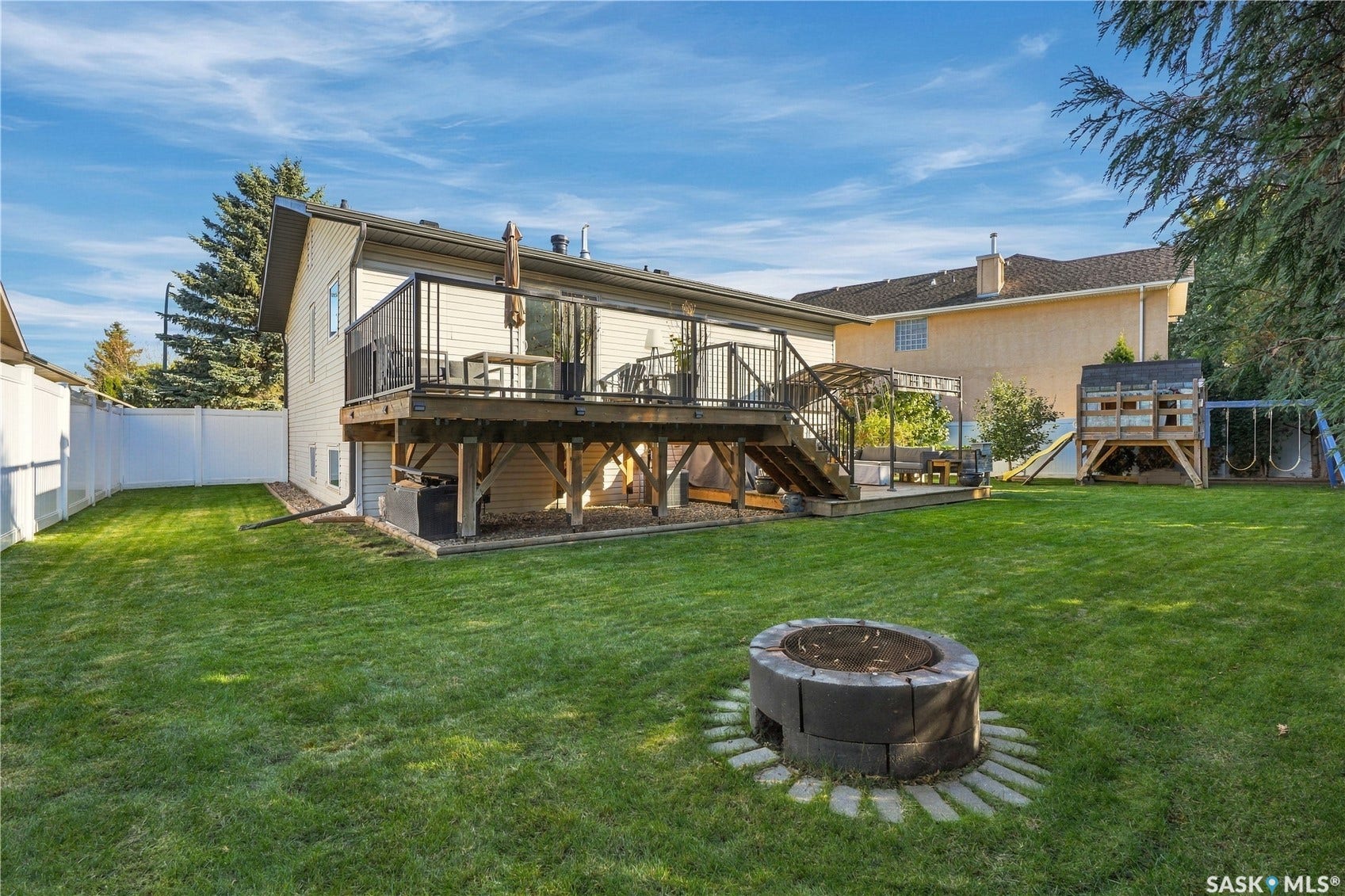 Expansive lawn featuring a built-in fire pit, privacy fencing, and a multi-level deck with black railings