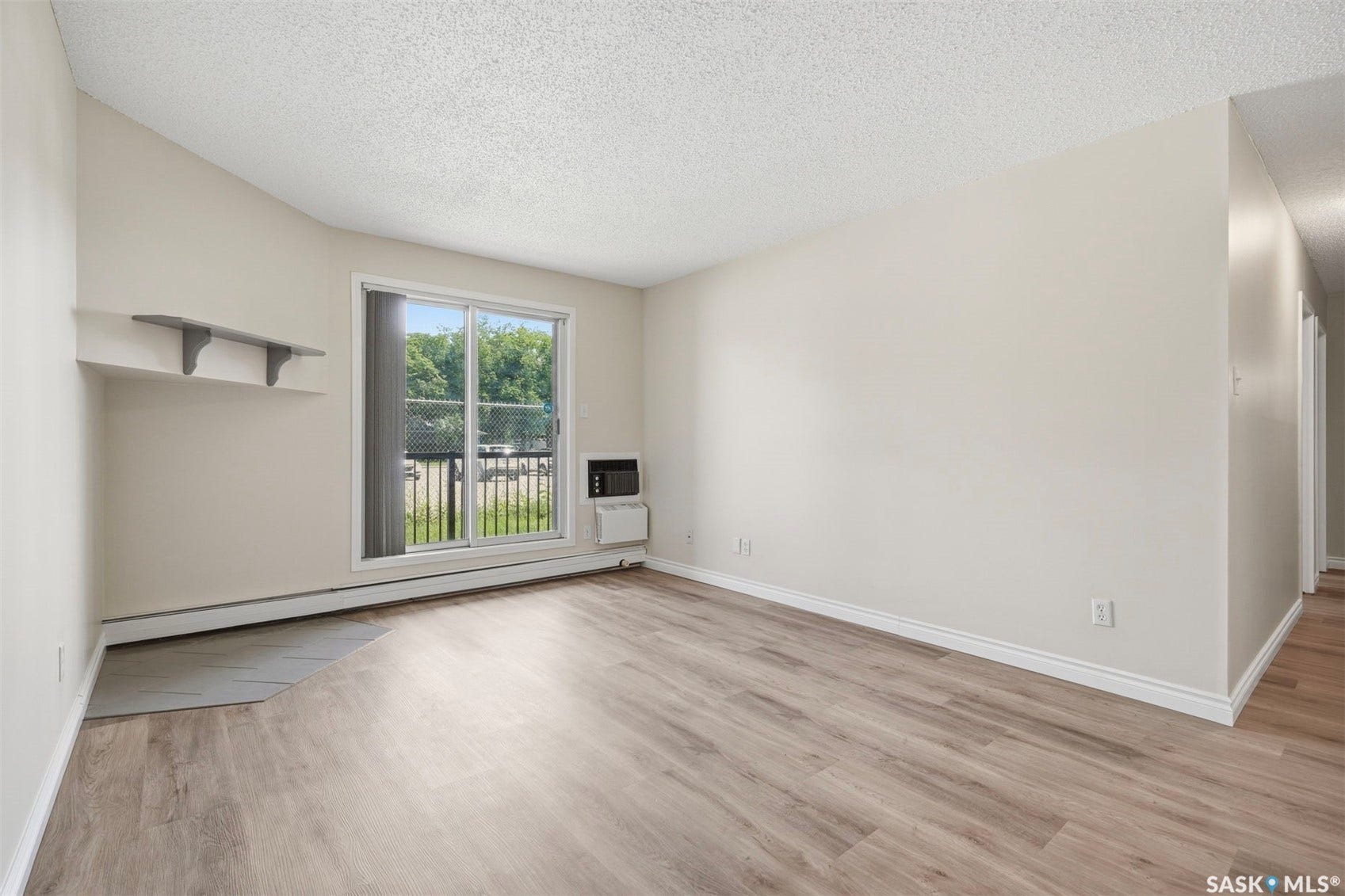 Wood-finish flooring, neutral wall paint, built-in shelving, sliding glass door, and a wall-mounted air conditioning unit