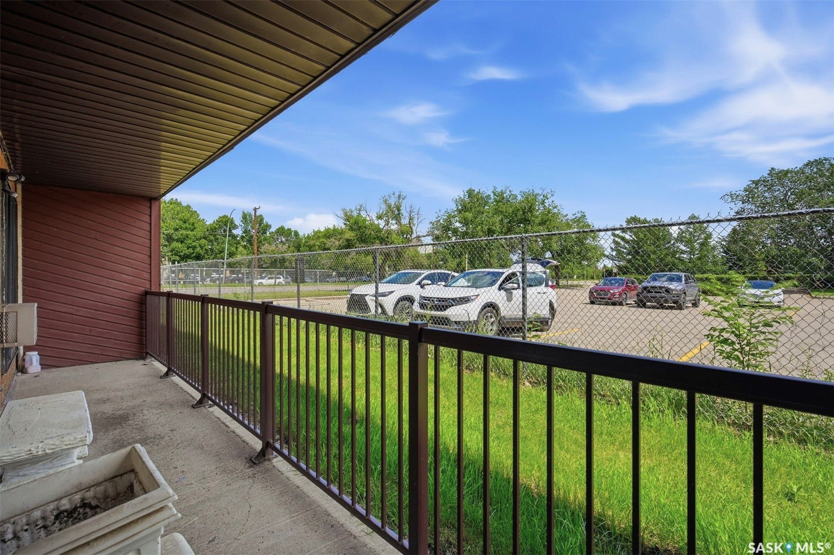 Covered outdoor patio with concrete flooring, brown siding, and dark metal railing