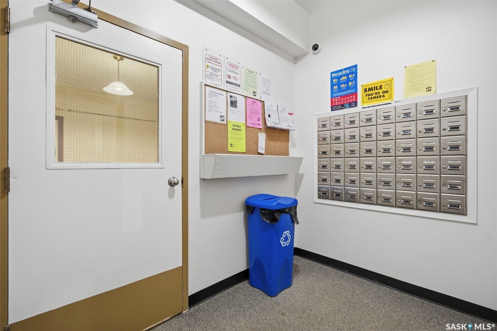 Mailroom area featuring individual mailboxes and a cork board