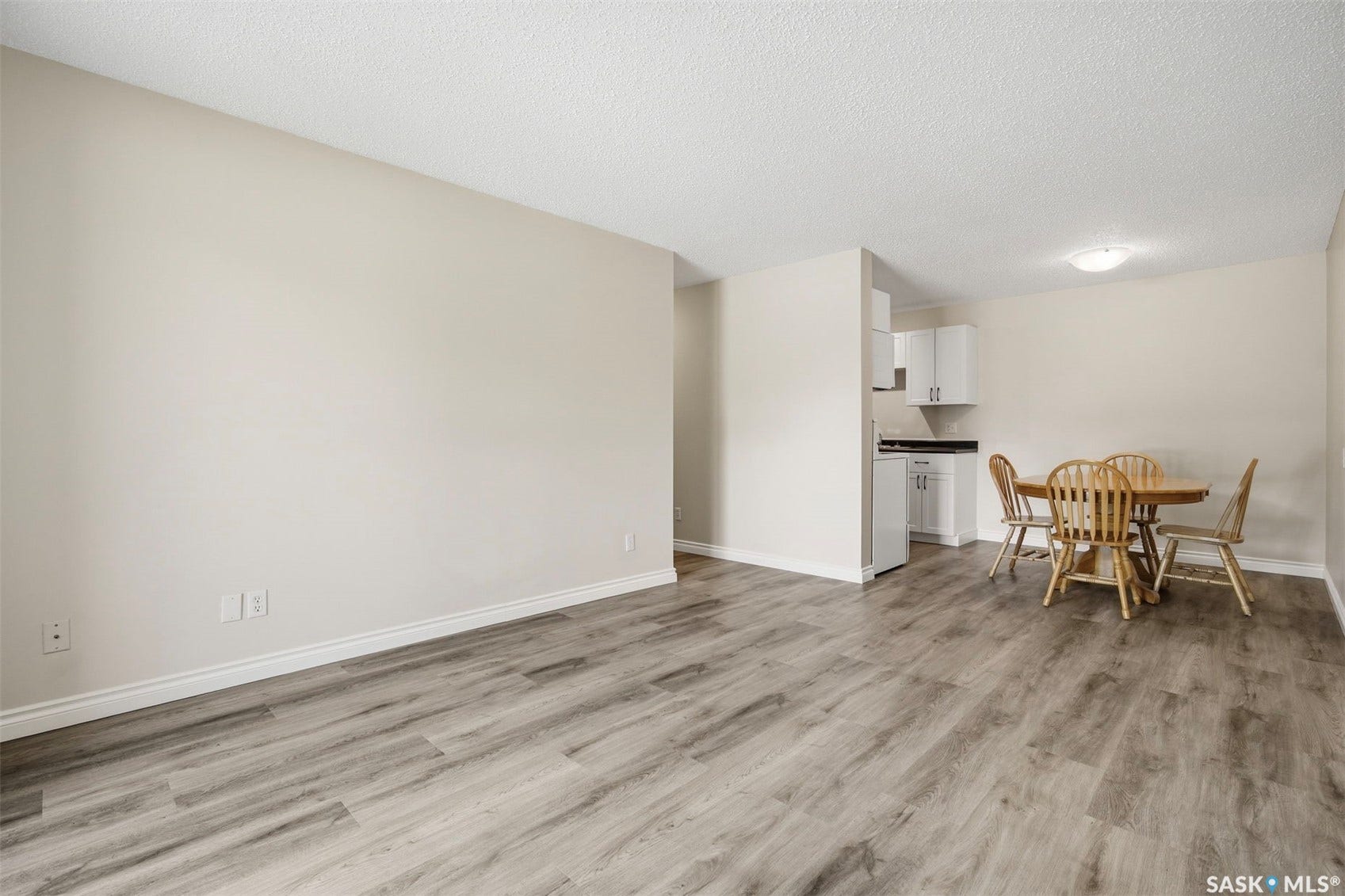Spacious open-concept living area featuring wood-finish flooring, neutral wall tones, and recessed ceiling lighting