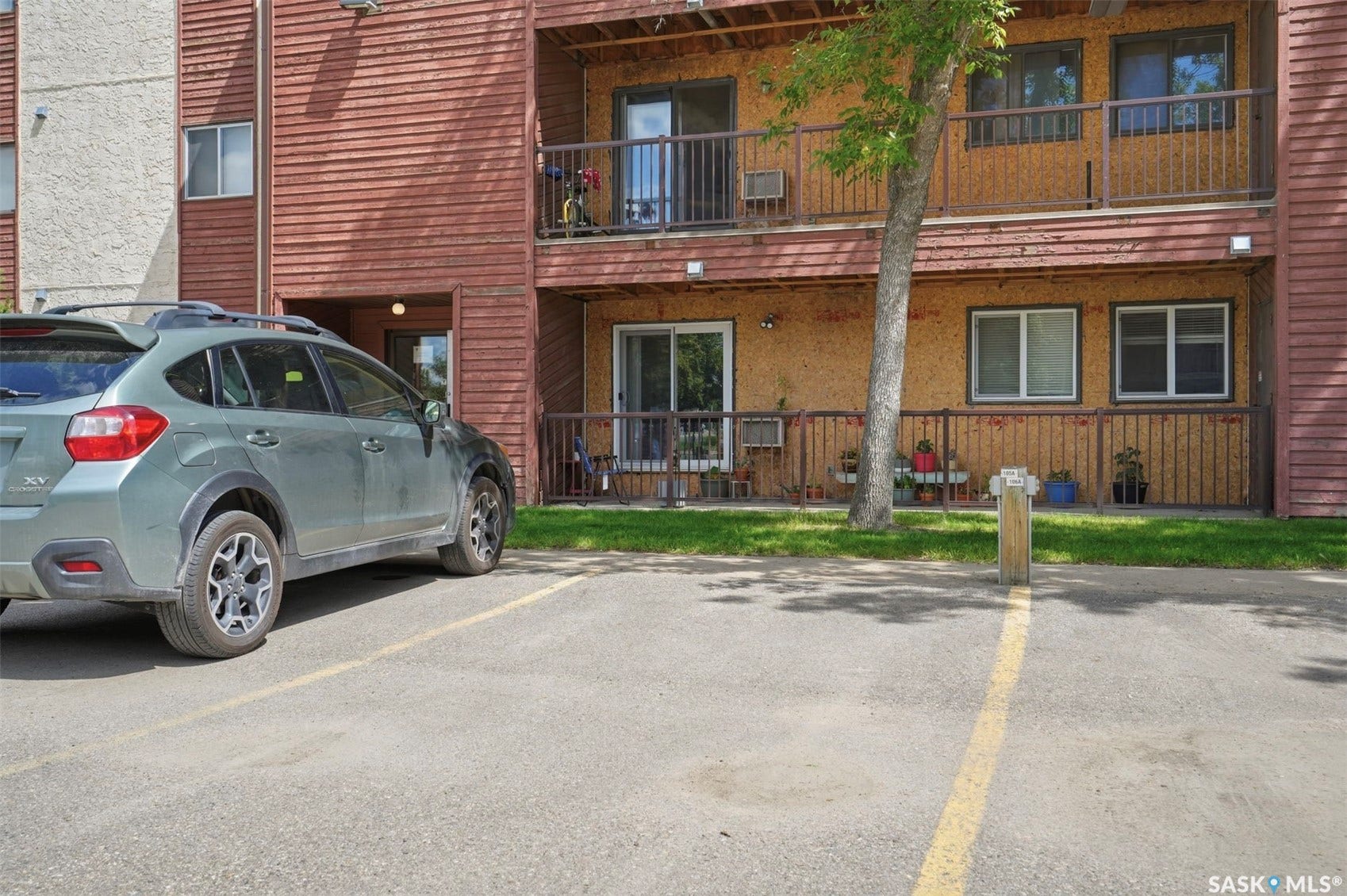 Exterior facade featuring horizontal wood siding, ground-level patio, and upper-level balconies with metal railings