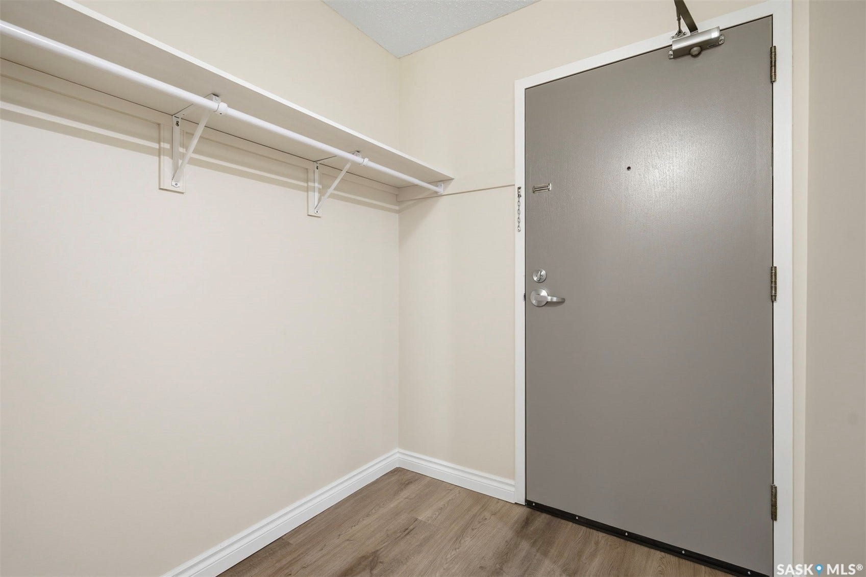Entry area featuring wood-finish flooring, light-toned walls, and a built-in shelf with a hanging rod