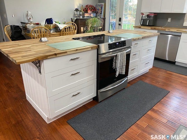 216 2nd Avenue, Wiseton SK S0L 3M0 Kitchen island with butcher block countertops, white shaker cabinetry, stainless steel range, and wood-finish flooring