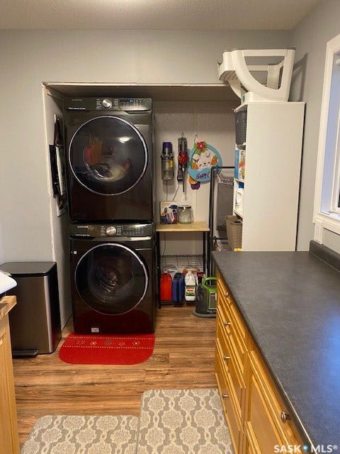 216 2nd Avenue, Wiseton SK S0L 3M0 Laundry area with stacked appliances, wood-finish flooring, and built-in cabinetry with a dark countertop