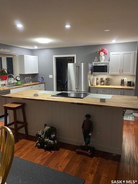 216 2nd Avenue, Wiseton SK S0L 3M0 Kitchen featuring an expansive island with a built-in cooktop, light wood-finish countertops, stainless steel appliances, and recessed ceiling lighting