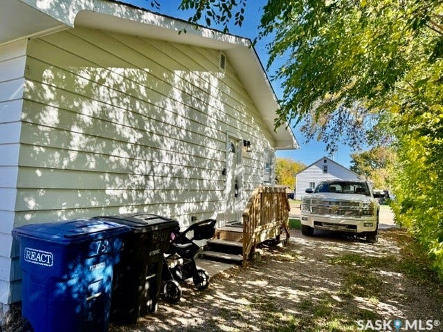 Side exterior featuring horizontal siding, a wooden deck, and gravel parking