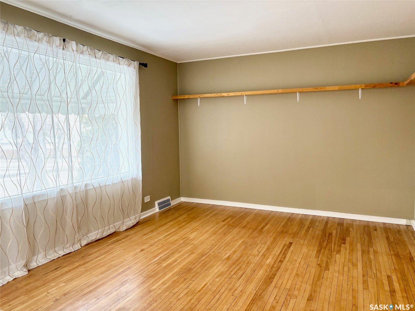 Hardwood flooring, neutral wall tones, crown molding, and window with natural light