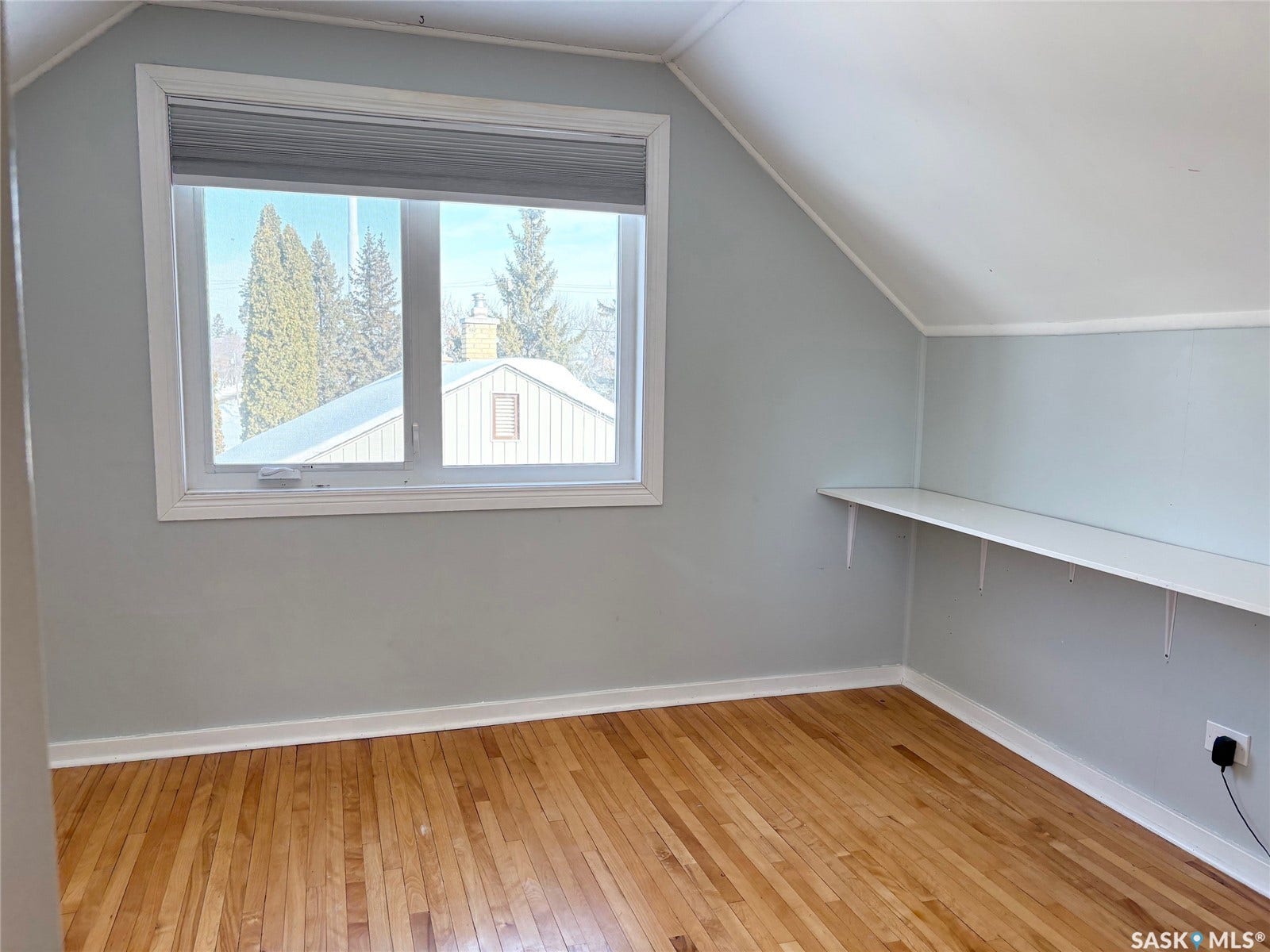 Wood-finish flooring with a large window, built-in shelving, and vaulted ceiling