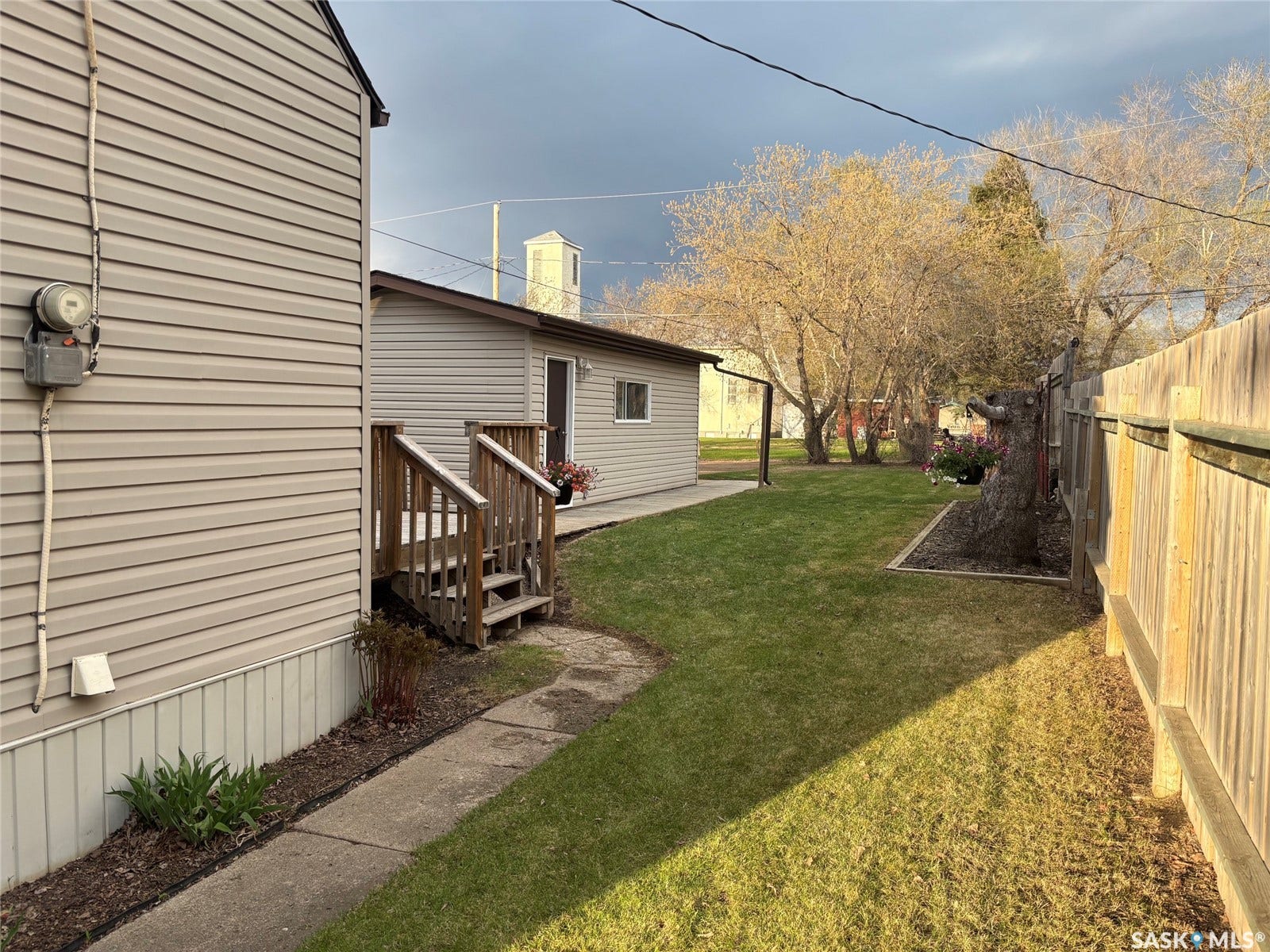 Expansive lawn, privacy fencing, dedicated concrete pathway, and multiple mature trees
