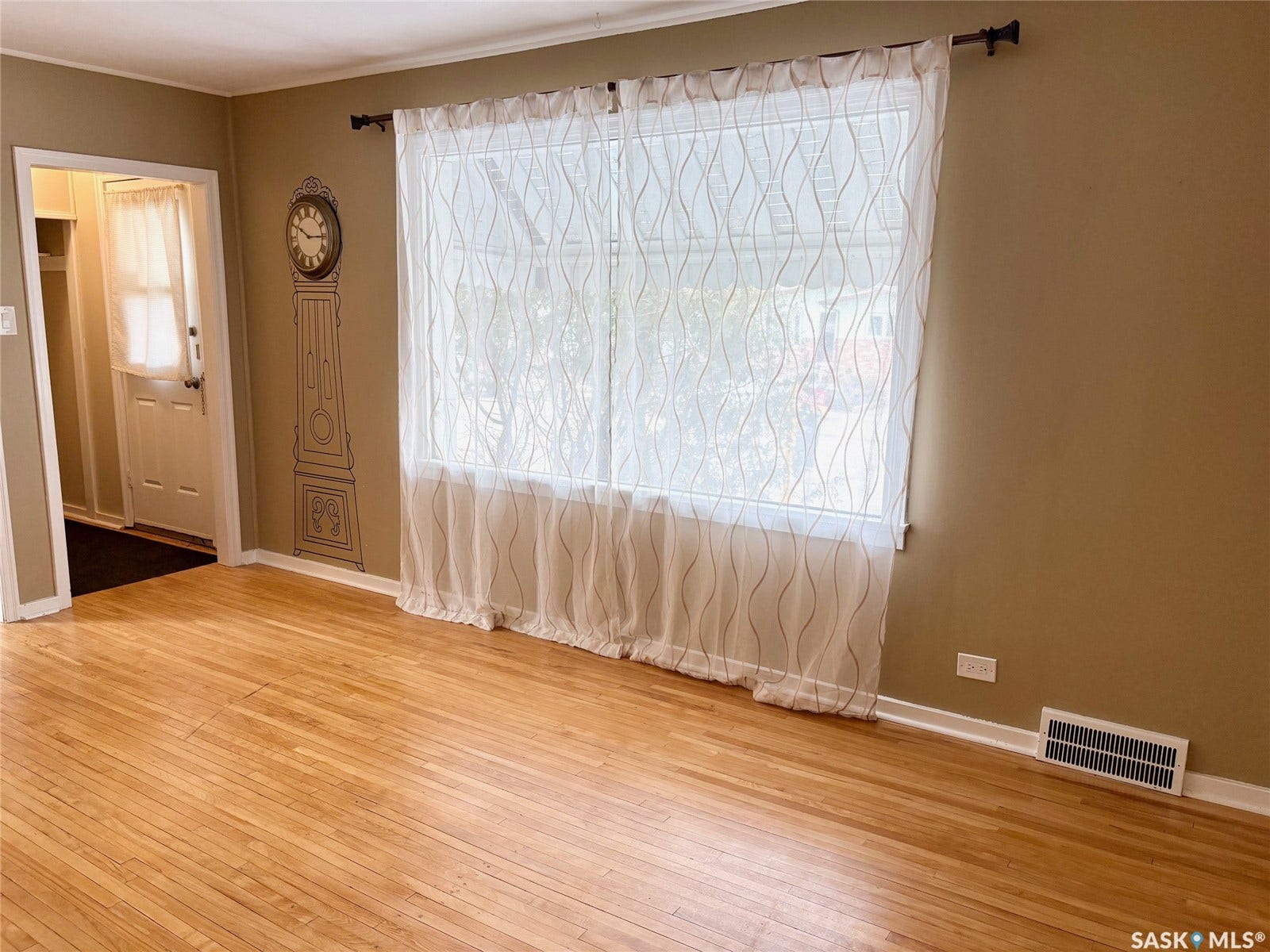 Hardwood flooring, painted walls, window with sheer curtains, white trim