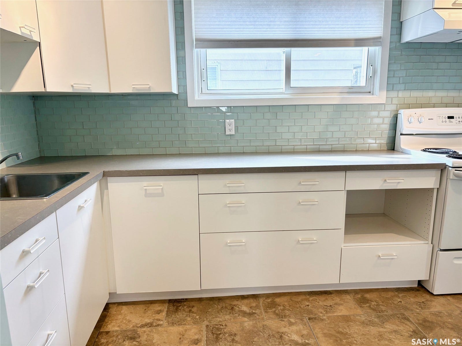 White cabinetry with concealed handles, light-toned countertops, and a subway tile backsplash