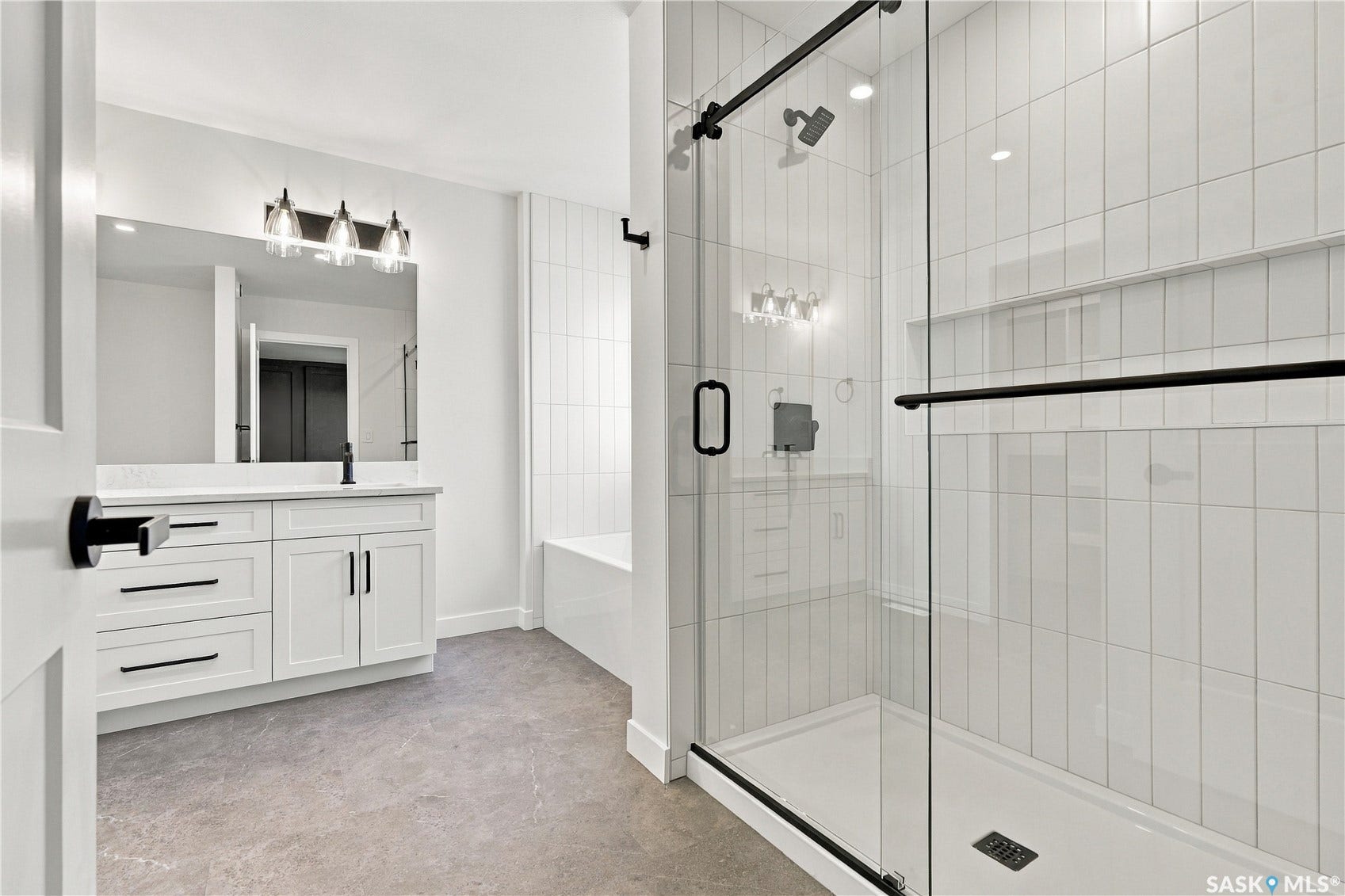 White shaker-style vanity with a light-toned countertop, large wall-mounted mirror, and black-finish hardware