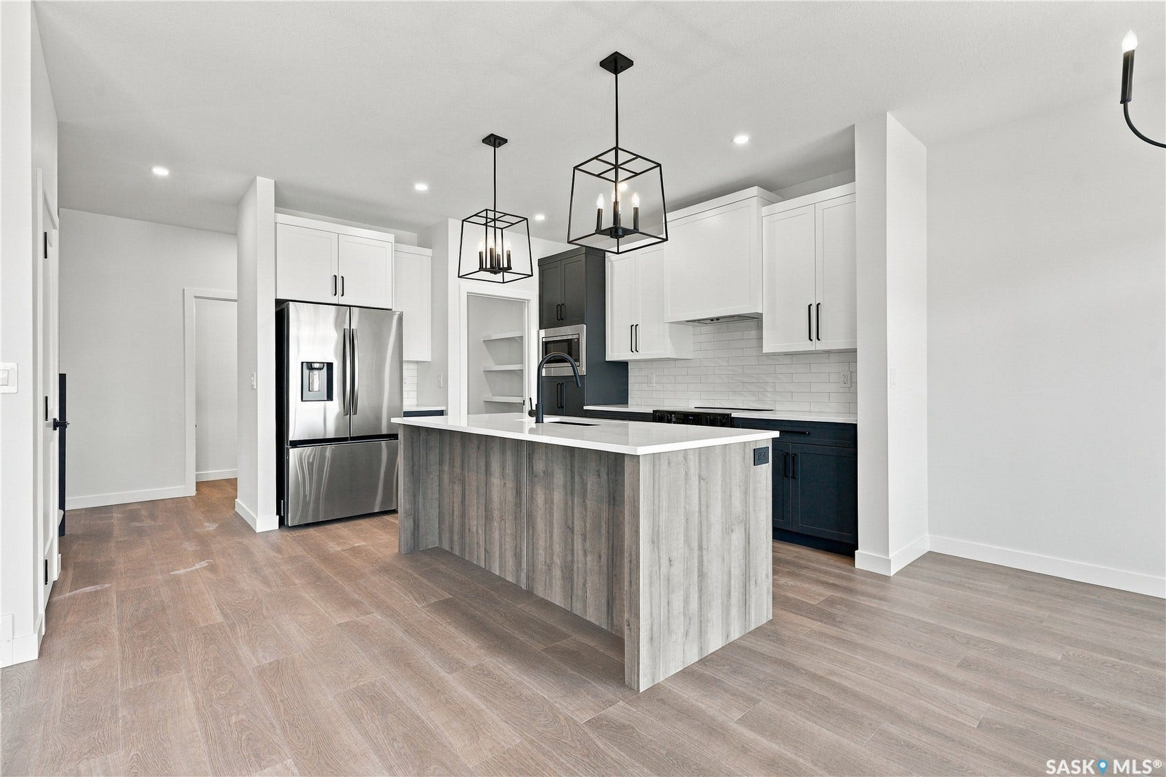 Modern kitchen featuring a wood-finish island, stainless steel appliances, white subway tile backsplash, and two-tone cabinetry