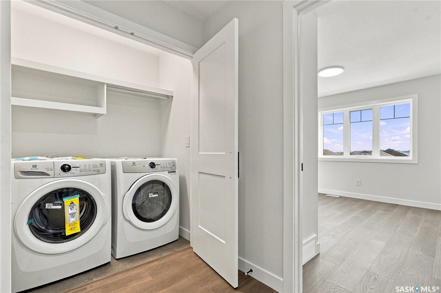 Built-in shelving with hanging rod, wood-finish flooring, white paneled door, three-panel window, flush-mount ceiling light fixture