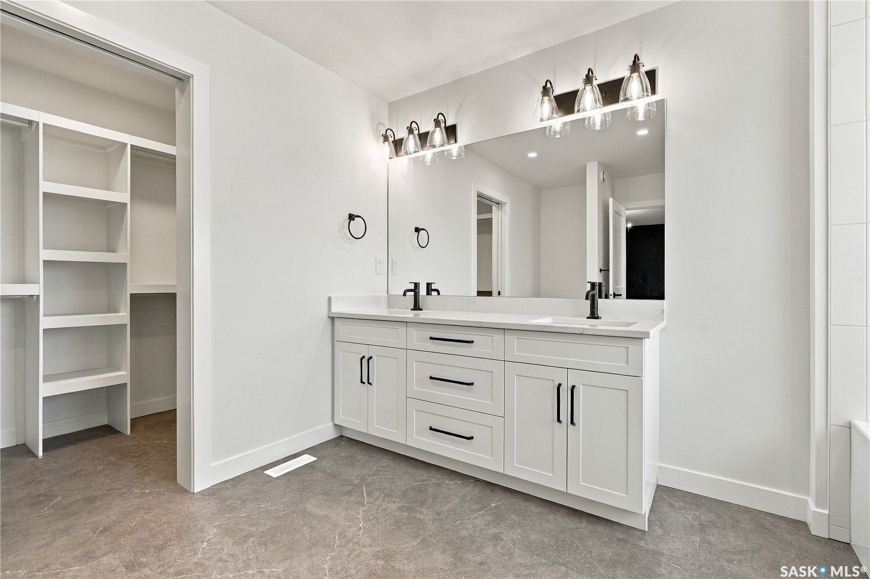 Dual vanity with white shaker-style cabinetry, matte black hardware, and integrated sinks