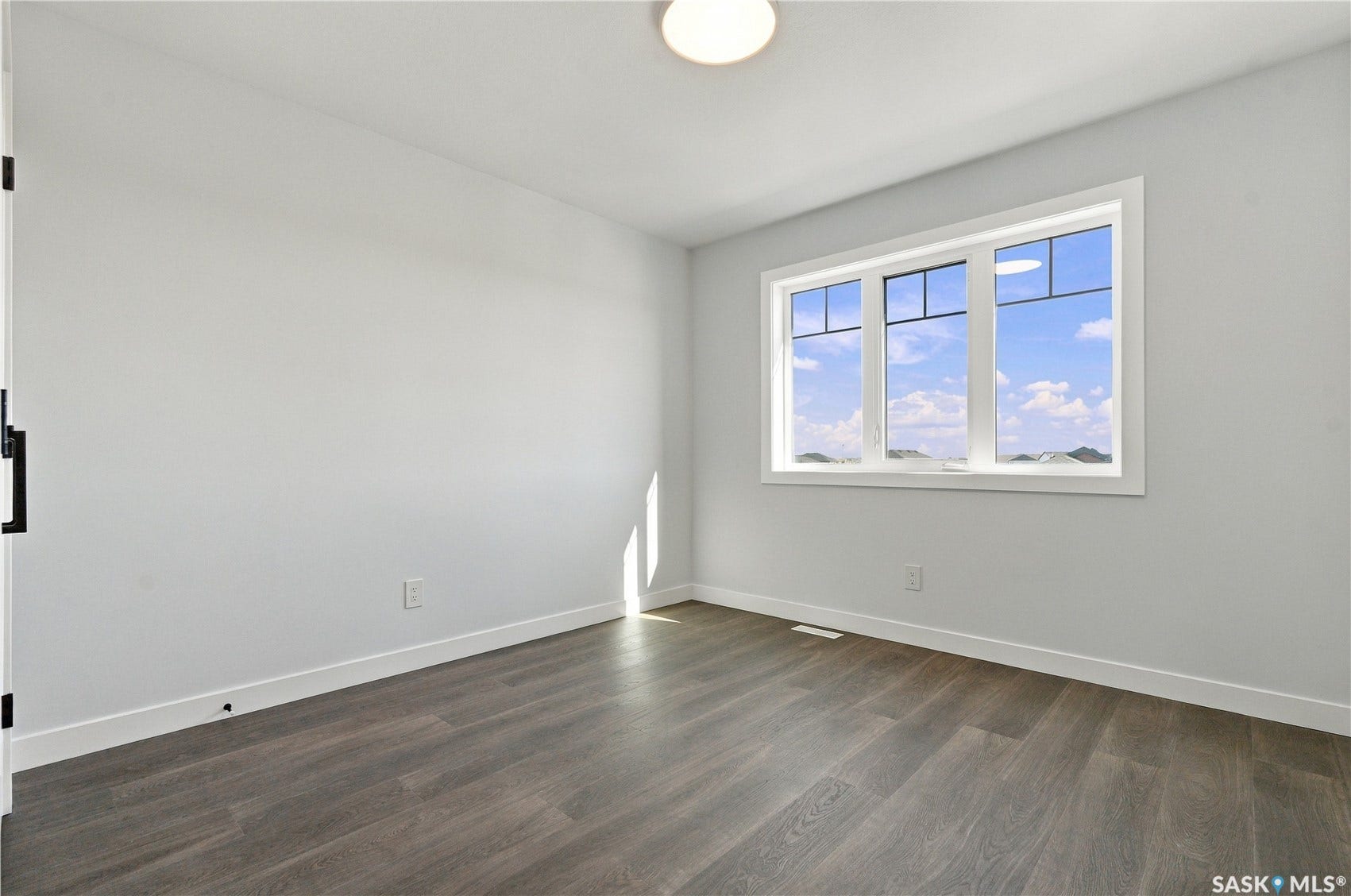 Wood-finish flooring, white walls, and a multi-pane window with white trim