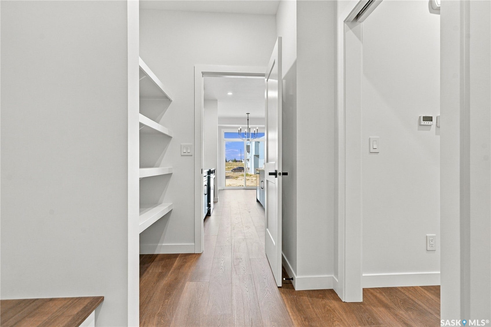 Built-in shelving, wood-finish flooring, white doors with black hardware, and ample natural light