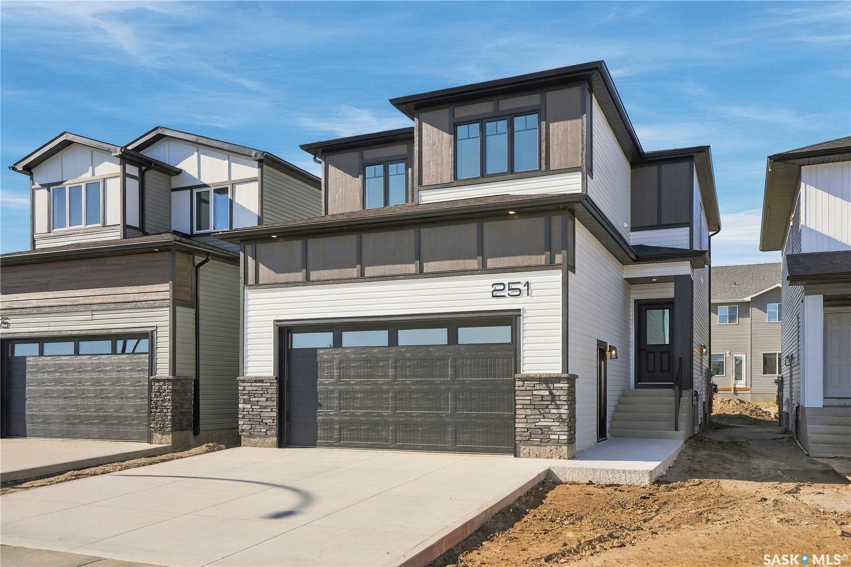 Modern two-story exterior with multi-toned siding, stone accents, and a large front-facing garage