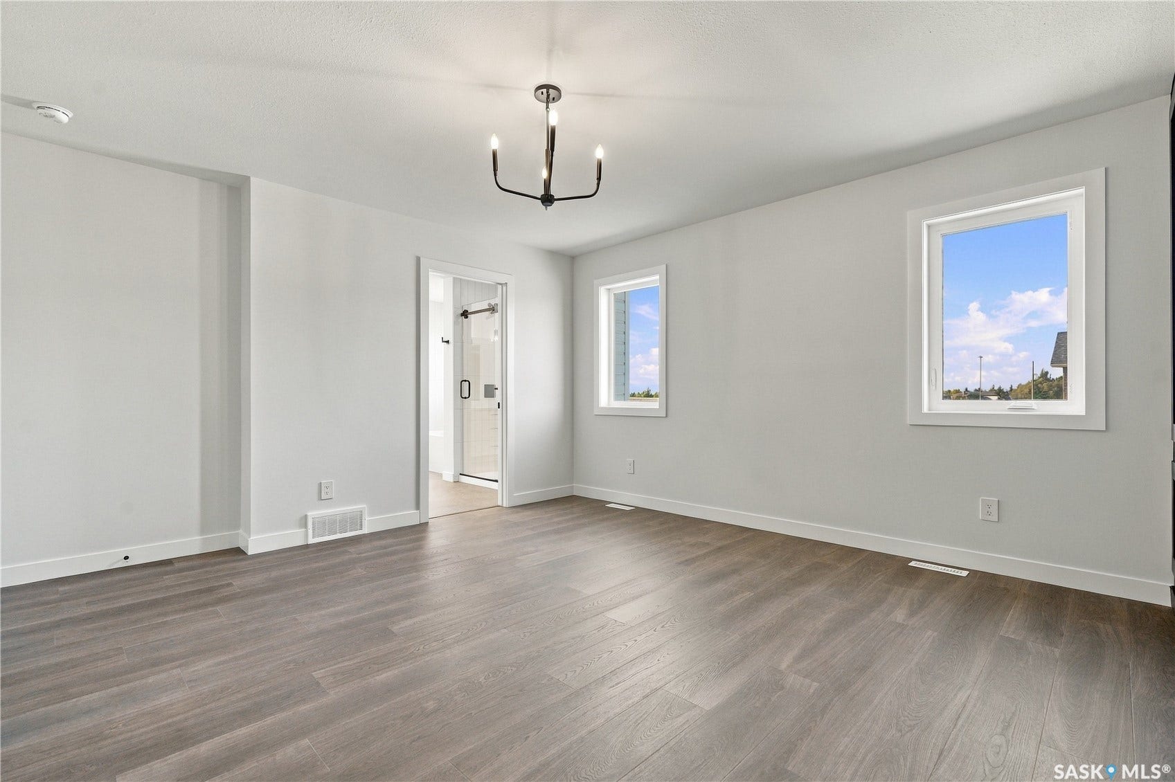 Wood-finish flooring throughout, multiple windows, and a black chandelier