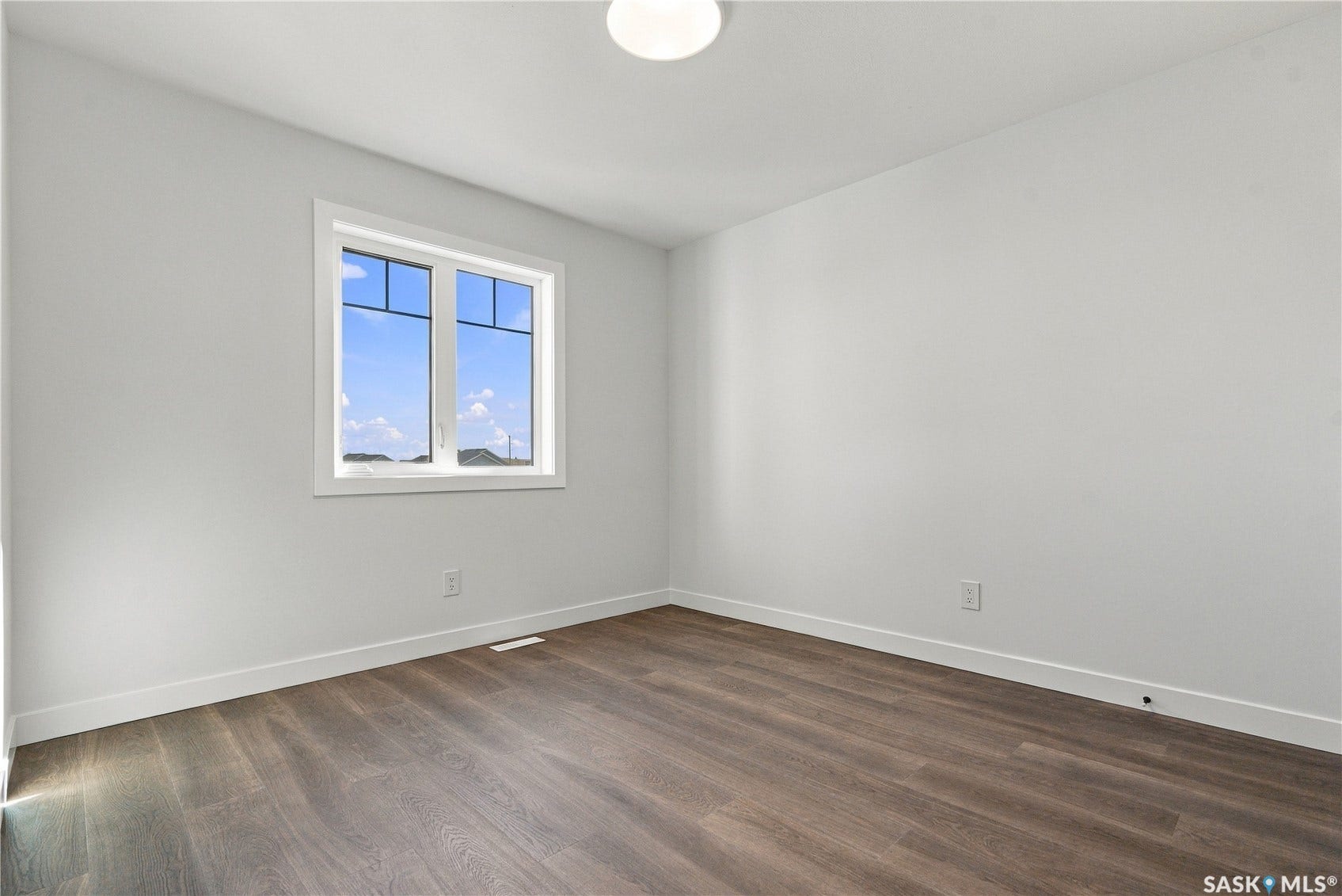 Bright room featuring a window with white trim, a flush-mount ceiling light, and wood-finish flooring