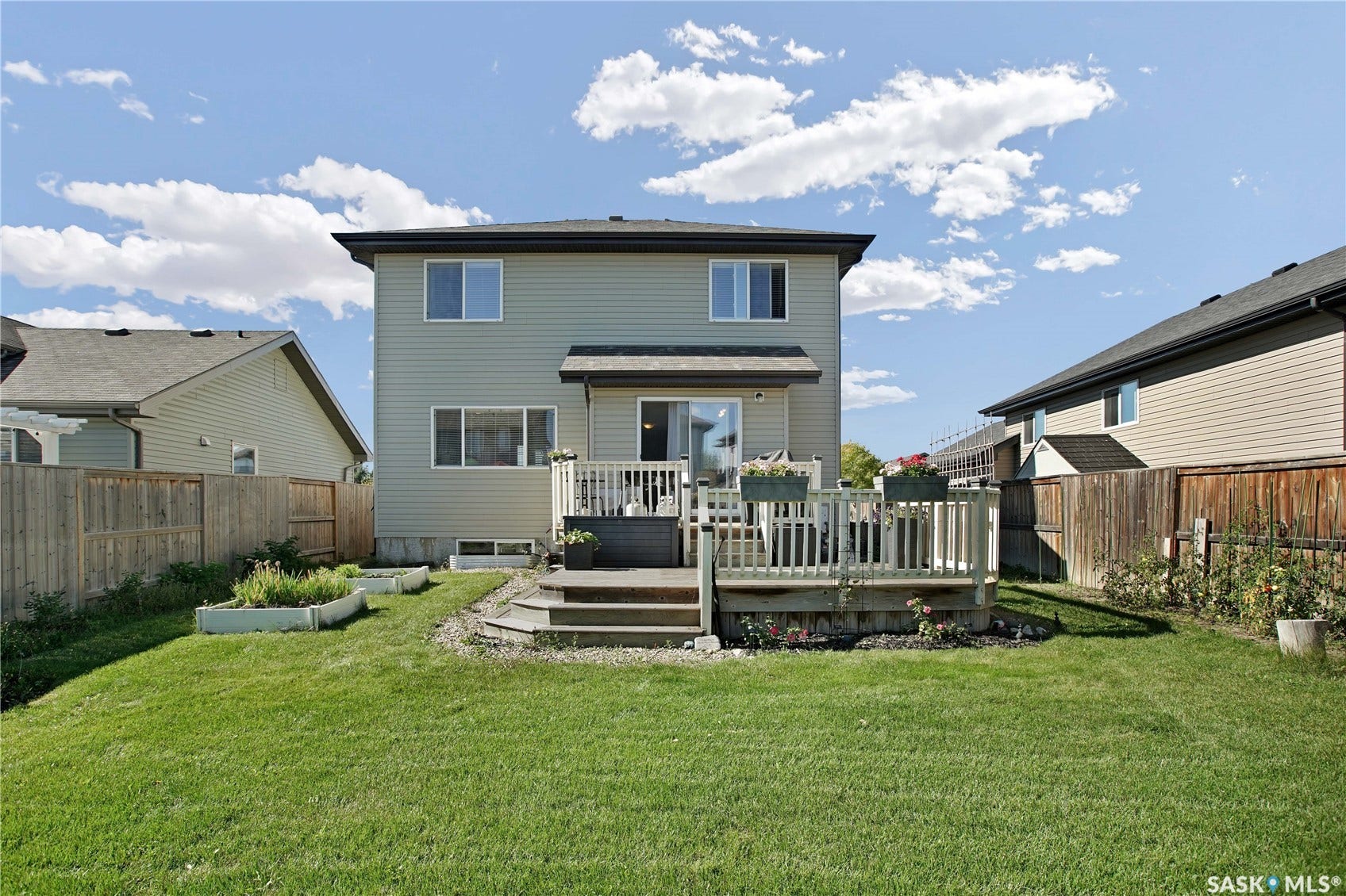 Well-maintained lawn, full privacy fencing, raised garden beds, multi-level wood deck, and sliding glass door access