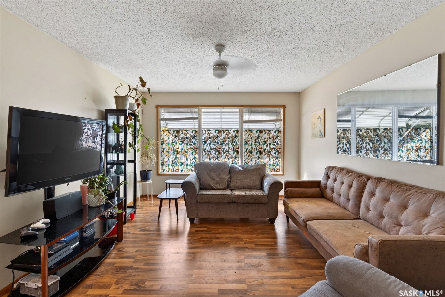 Wood-finish flooring throughout, multiple pane windows, and a ceiling fan with integrated lighting