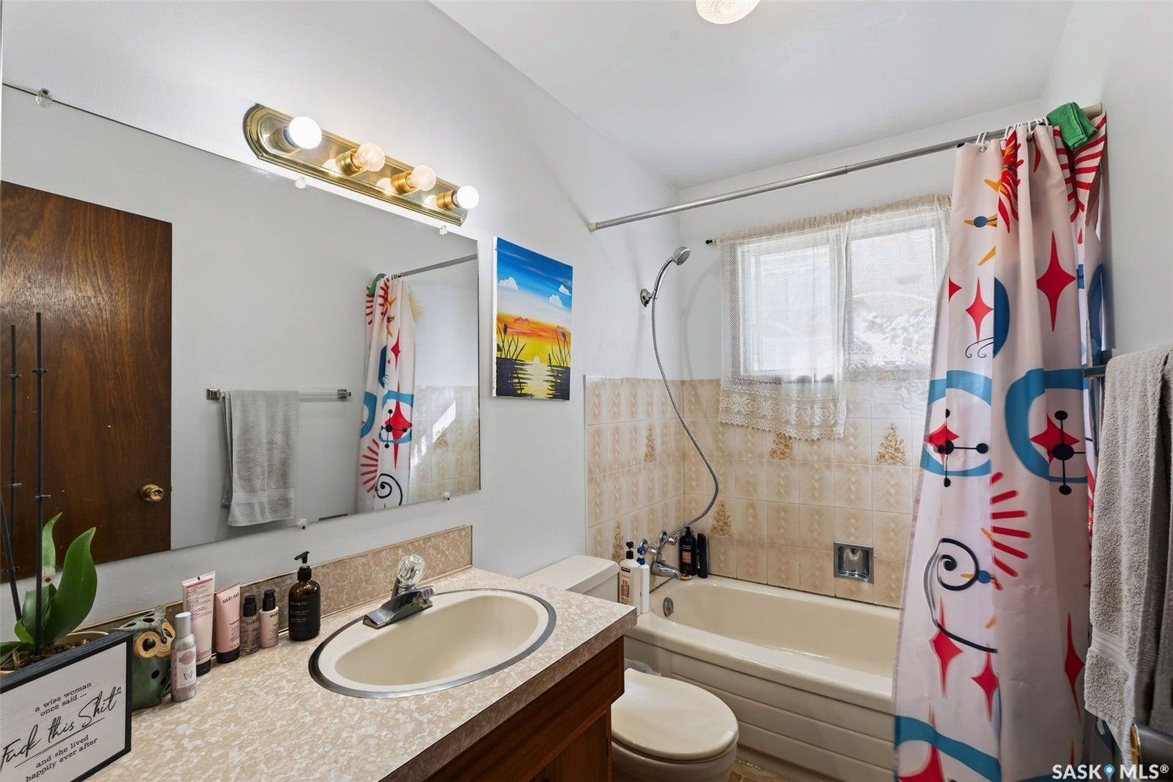 Bathroom featuring a built-in vanity with a countertop sink, an extended wall mirror, and a shower-over-tub combination with a window