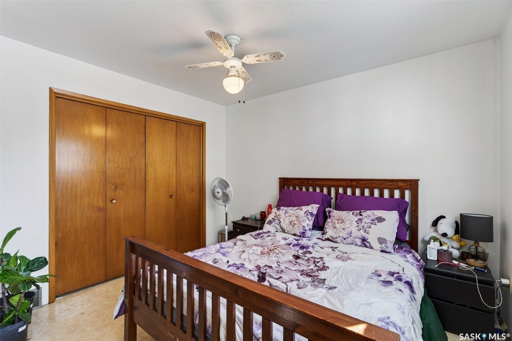 White walls, wood-finish bi-fold closet doors, and a ceiling fan