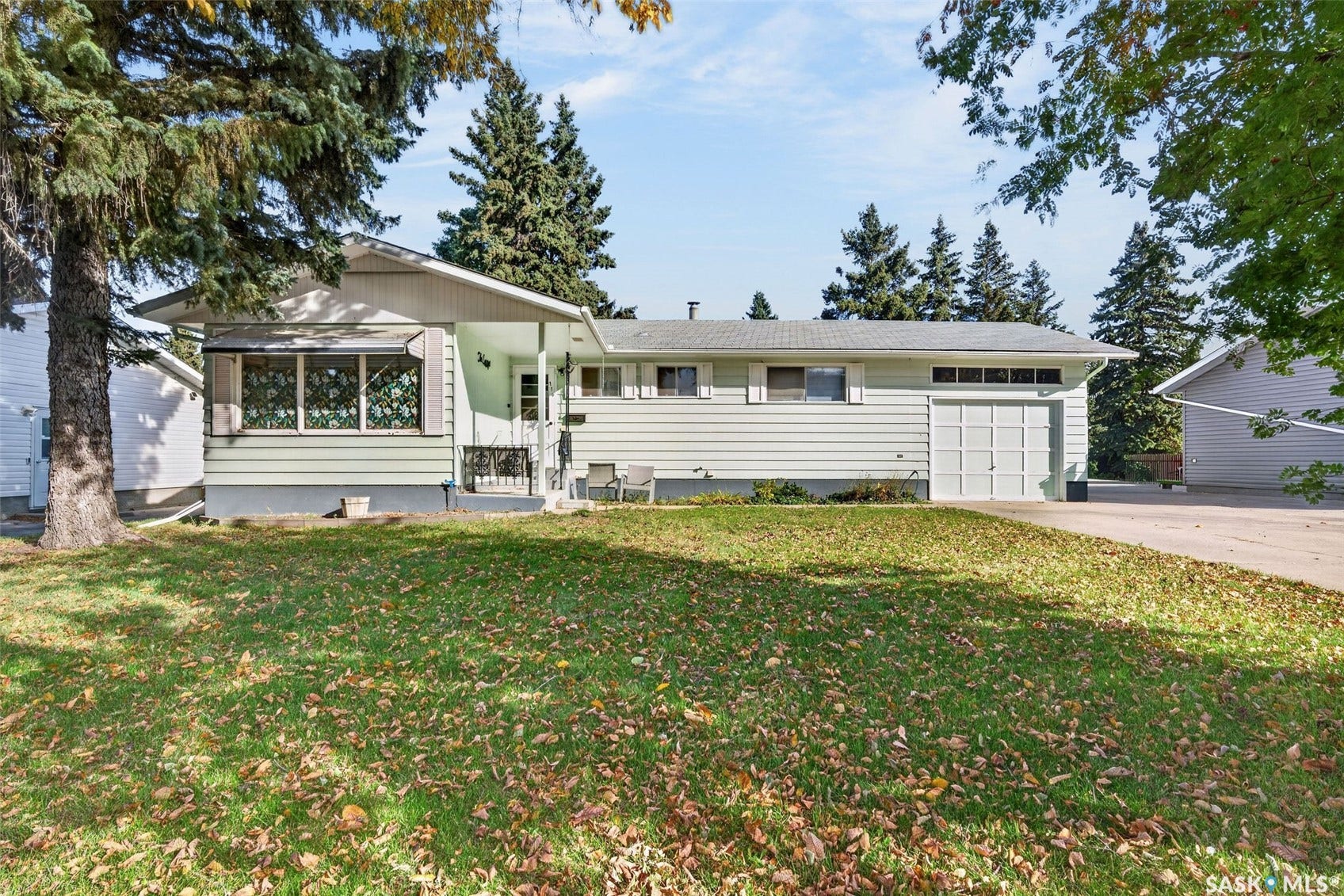 Single-story residence featuring light siding, a covered front entry, and a front-facing garage with a paneled door