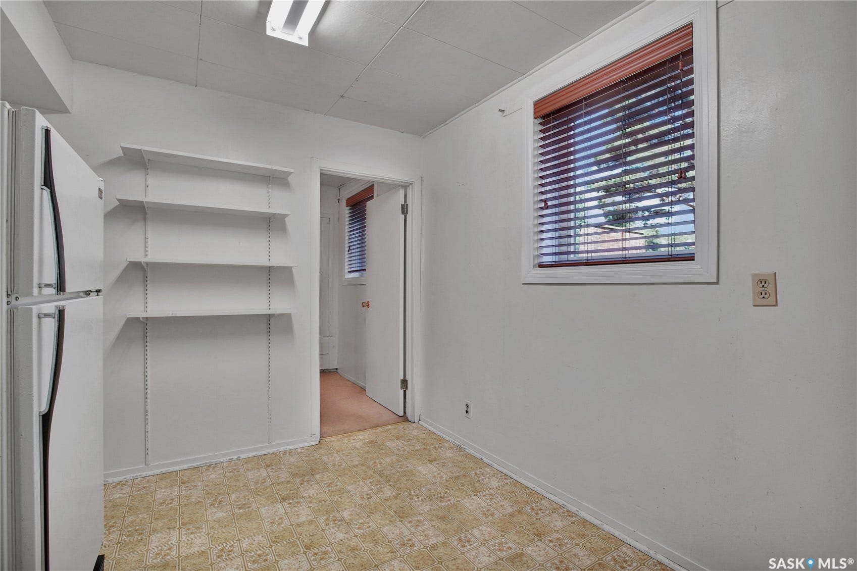 Adjustable wall shelving, window with blinds, and durable flooring