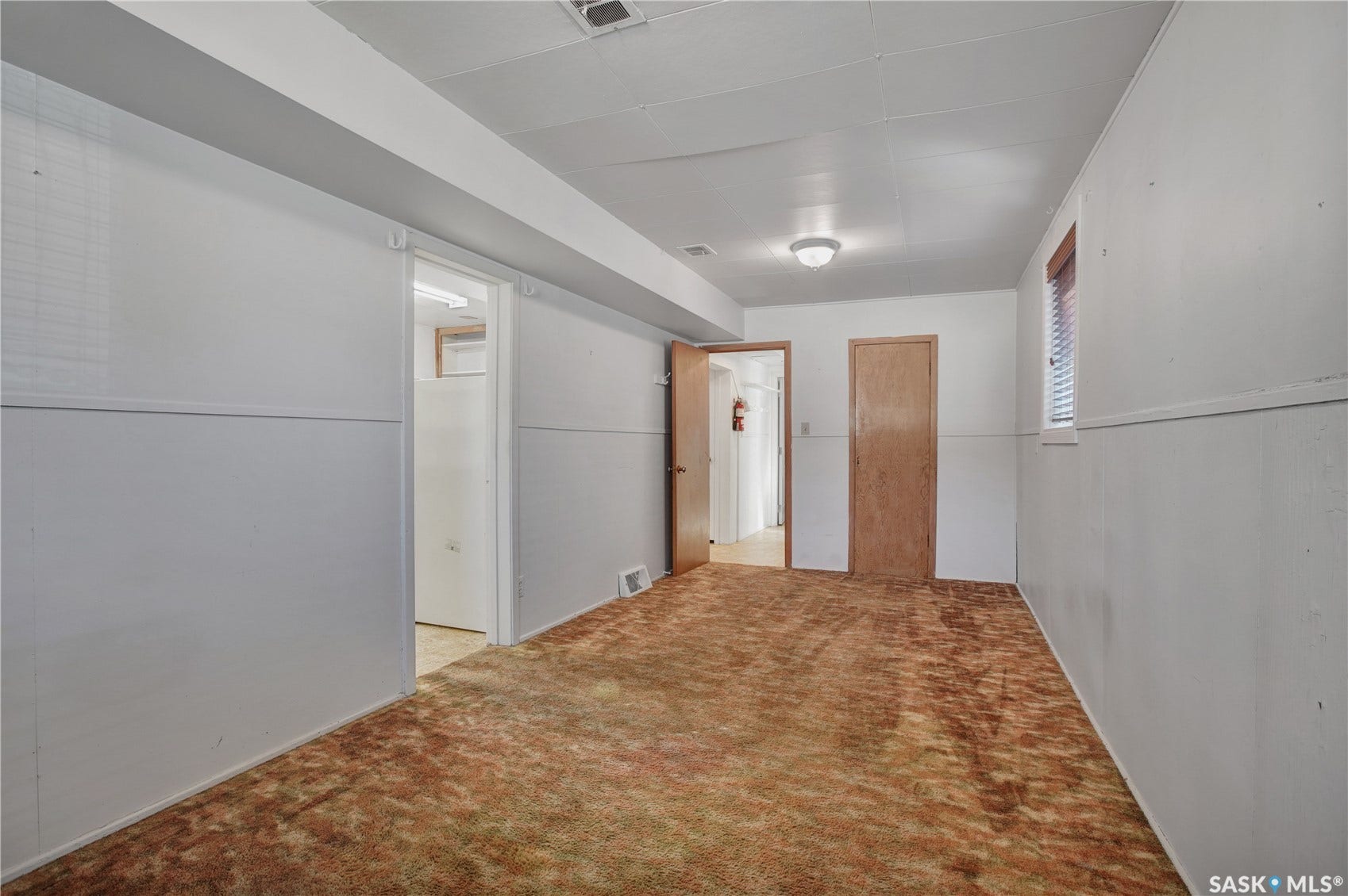 Recessed ceiling light fixture, wood-finish interior doors, and a window with blinds