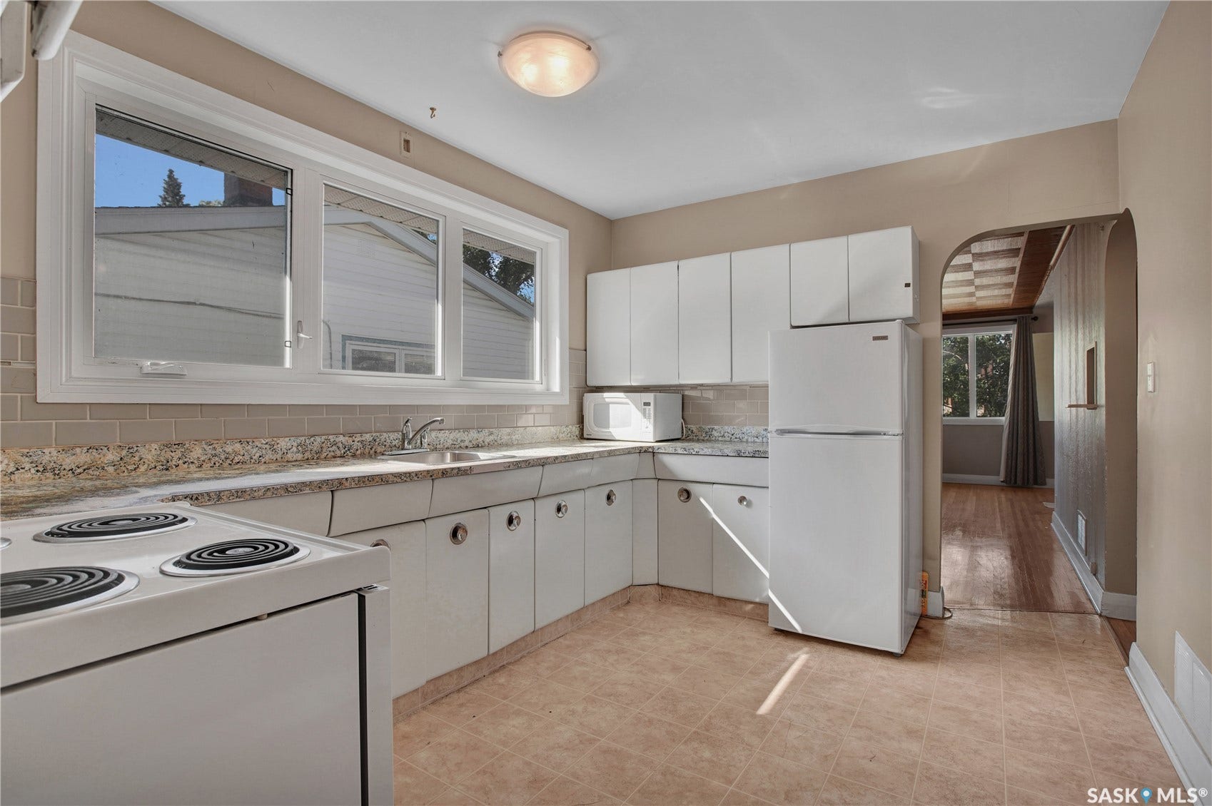 Kitchen featuring white cabinetry, light-toned countertops, a tile backsplash, and a ceramic tile floor