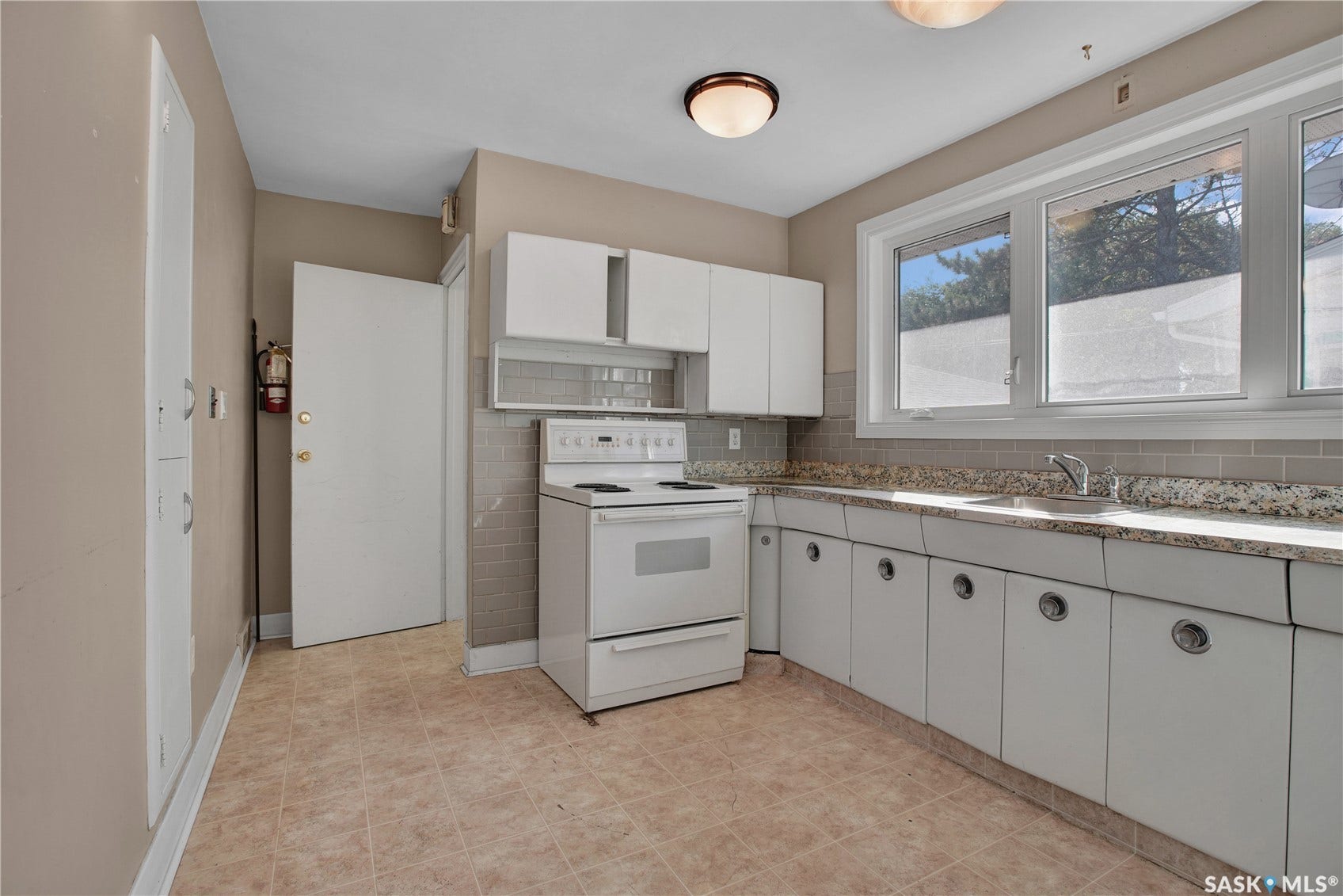 Kitchen featuring white cabinetry, a light-toned tile backsplash, a built-in range, and a dual-basin sink