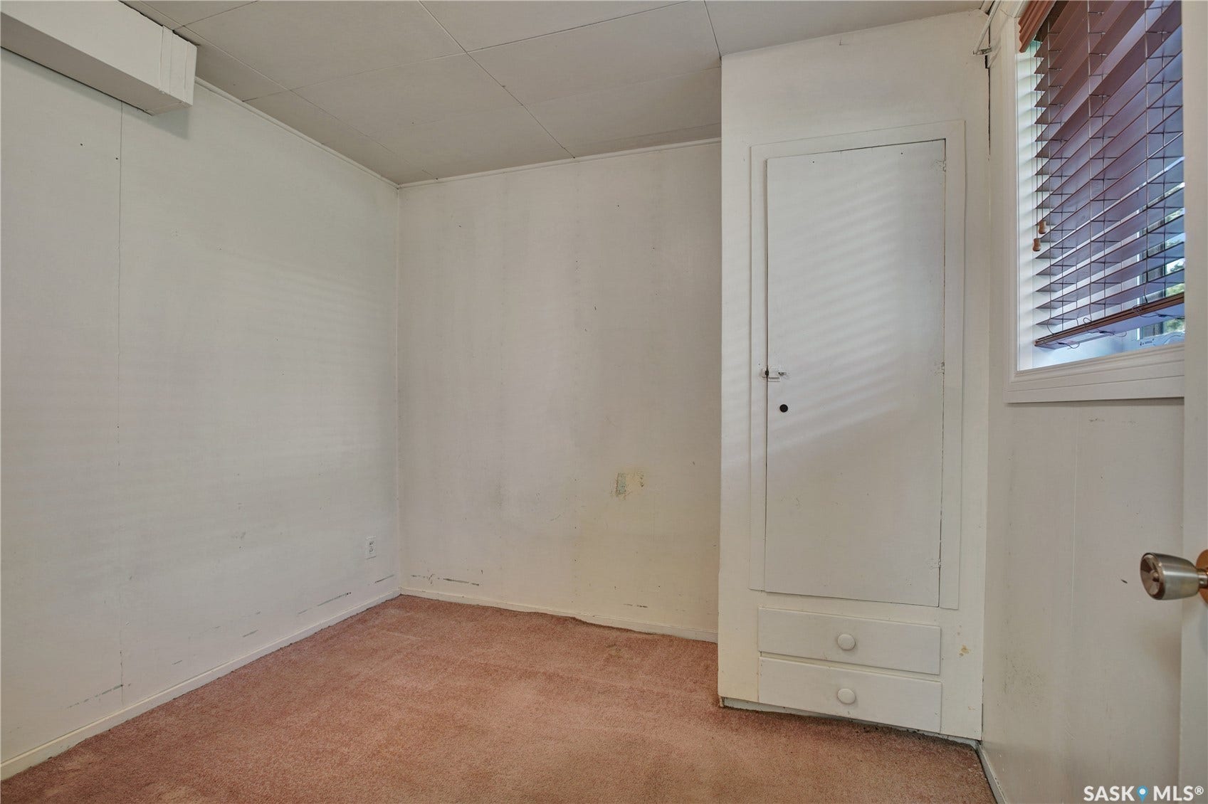 Built-in cabinetry with lower drawers, carpeted flooring, and window with horizontal blinds