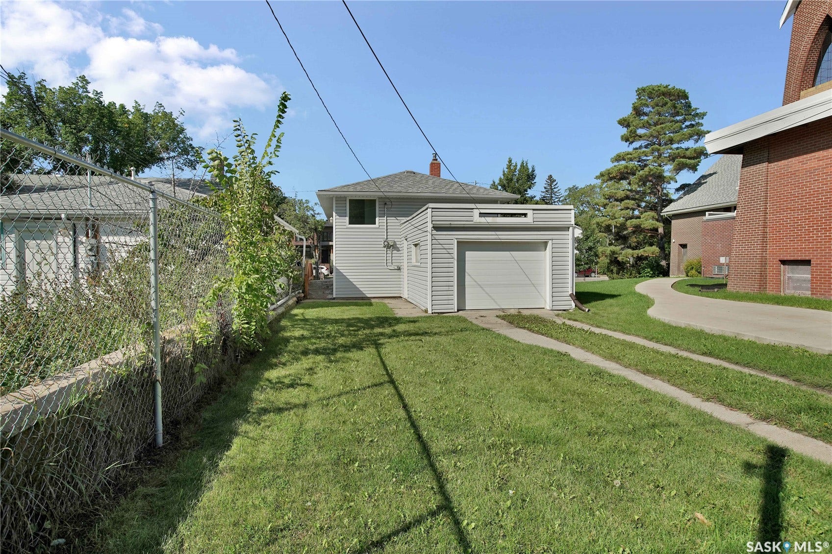 Detached structure with an integrated garage, featuring light-colored siding and a gabled roof