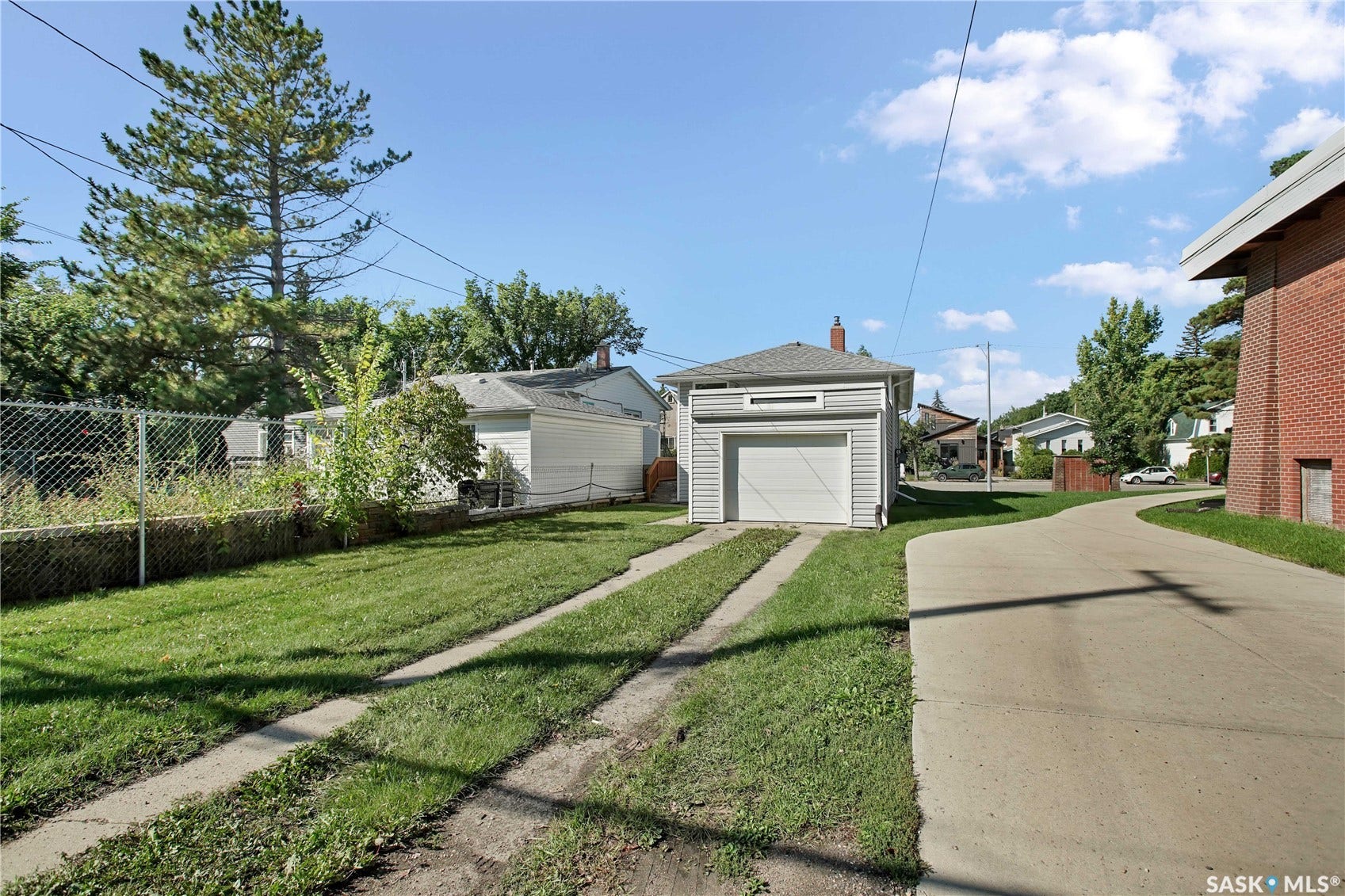 Detached garage with horizontal siding and a single garage door, alongside a paved driveway