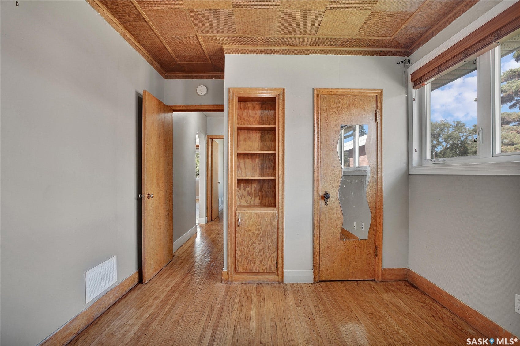 Wood-finish flooring, wood-paneled ceiling, built-in shelving, wood-finish doors, and a multi-pane window